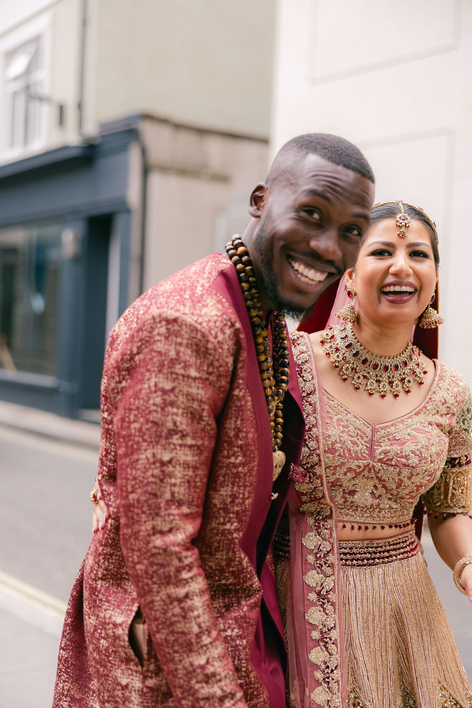 Couple in traditional wedding attire sharing laughter during their fusion ceremony.