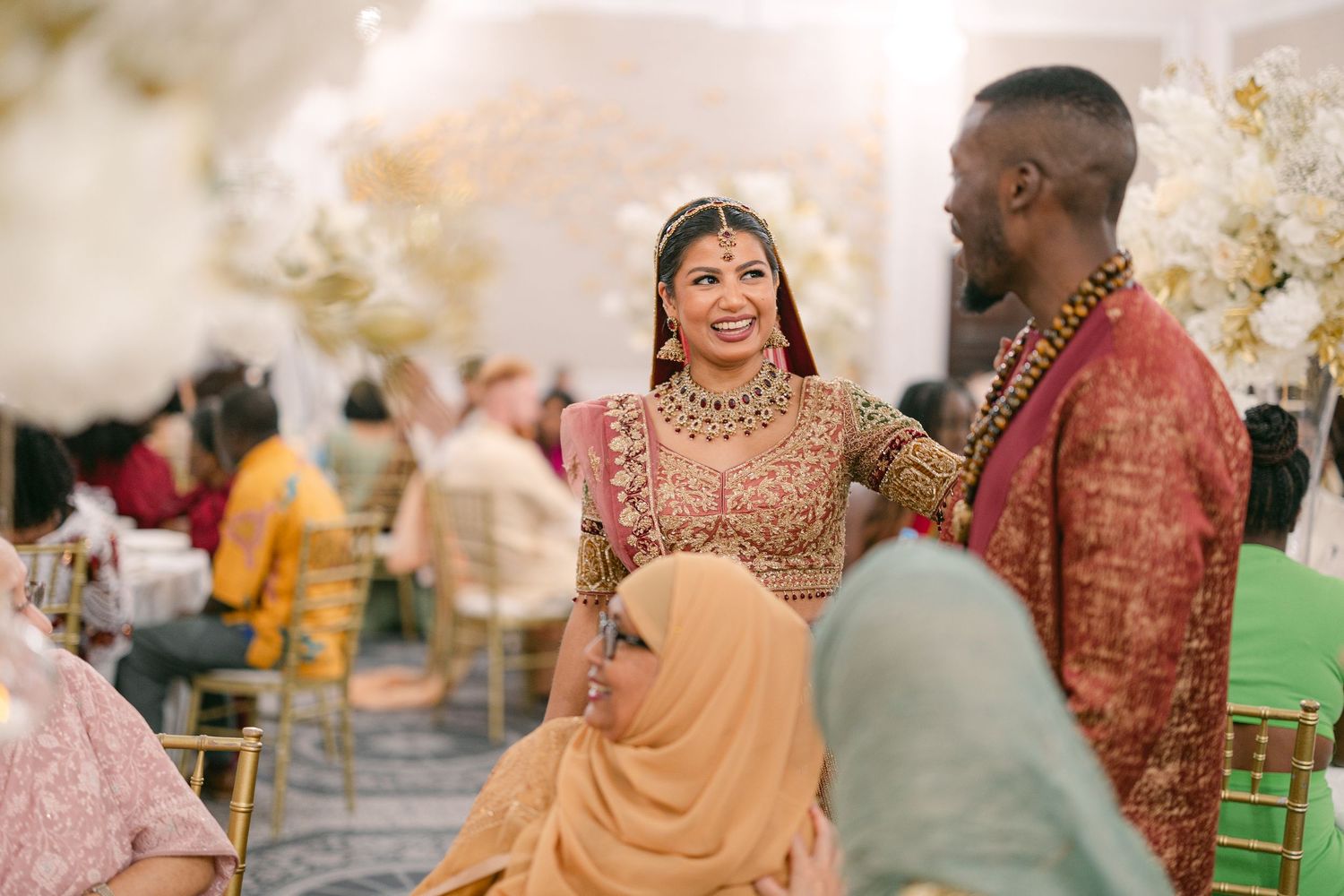 Wedding celebration scene with guests in traditional Indian attire gathered at an outdoor venue.
