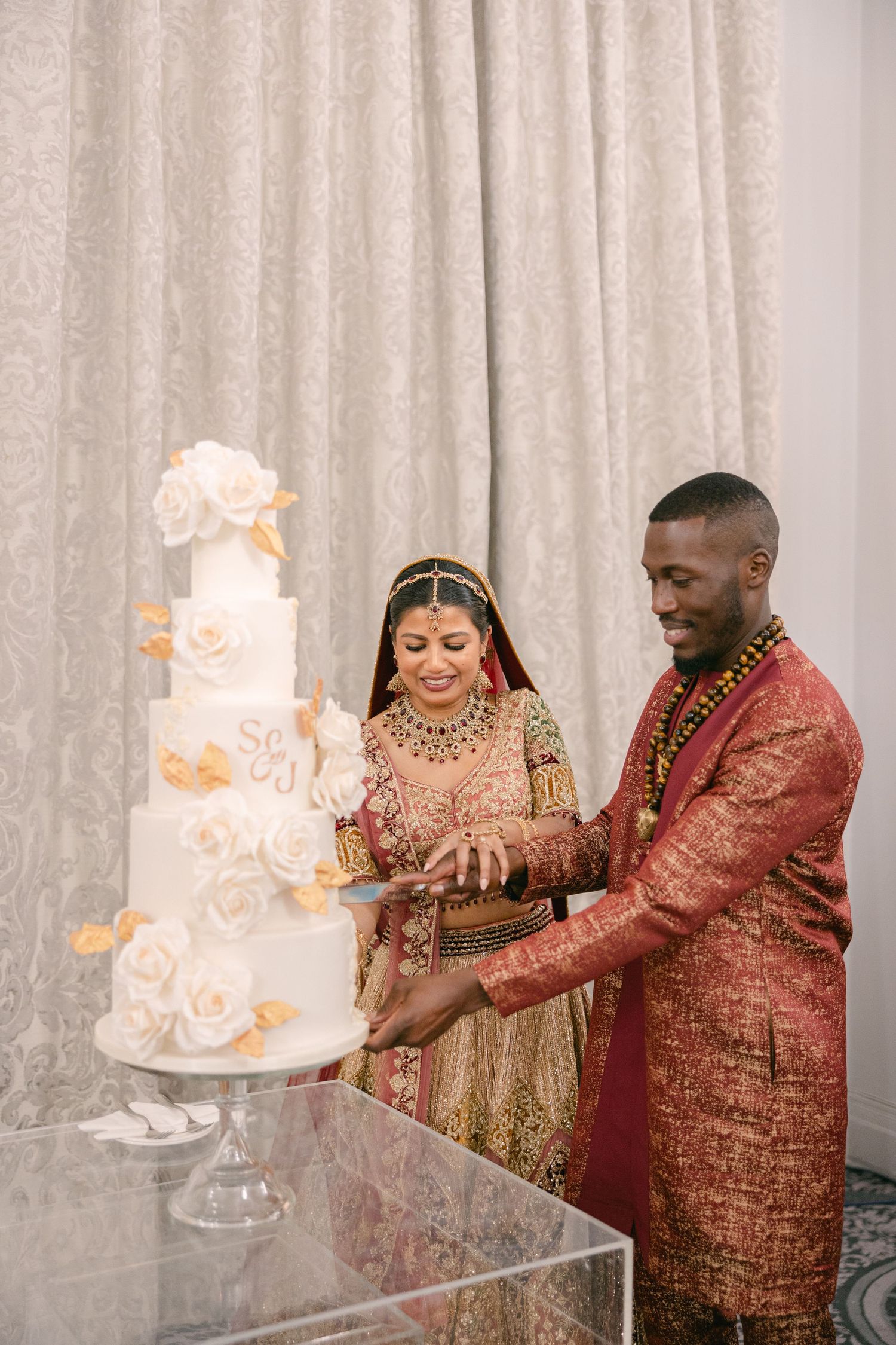 Newlyweds cutting their elegant white wedding cake together during their reception celebration.