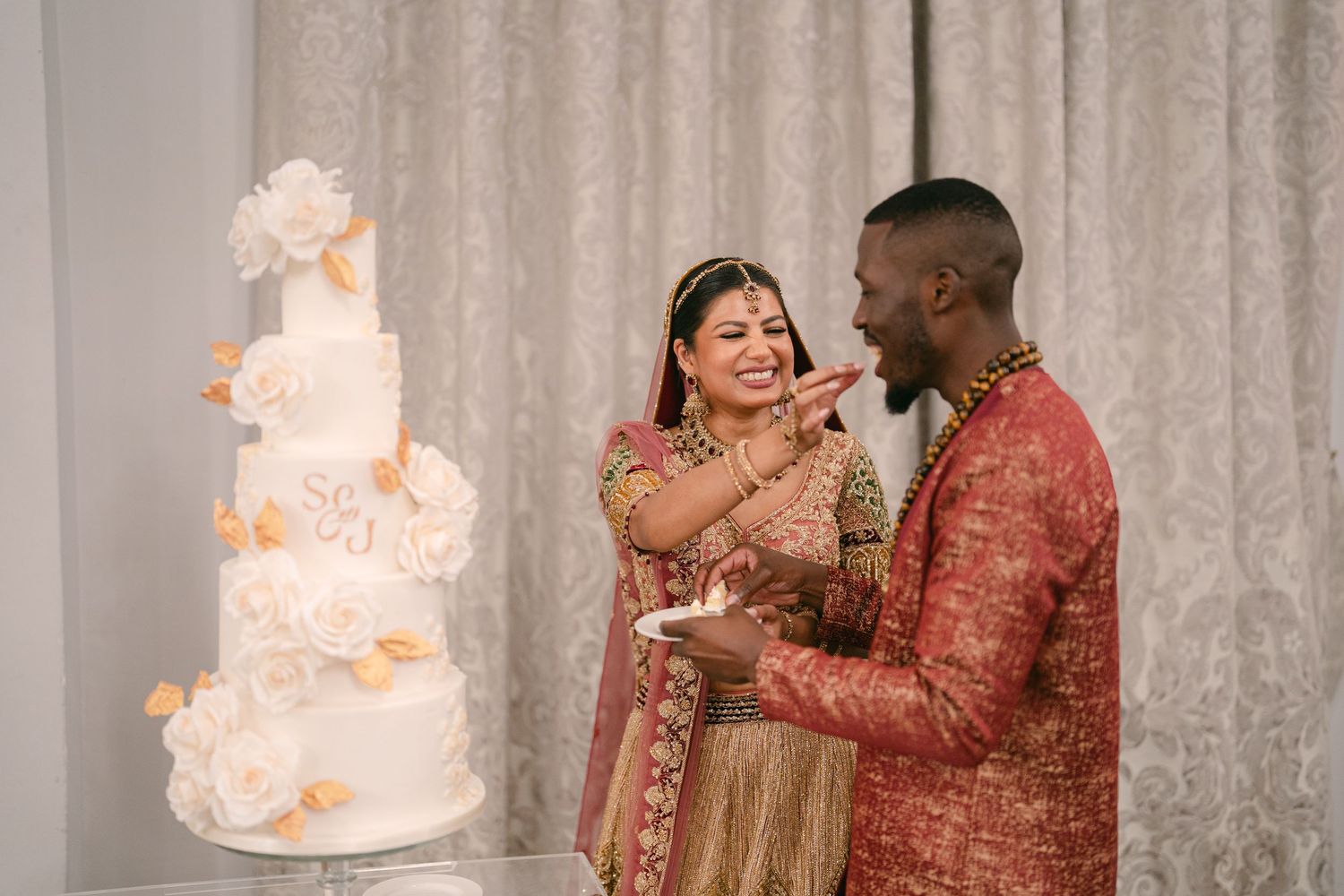 Wedding couple cutting their elegant white tiered cake together at their reception.