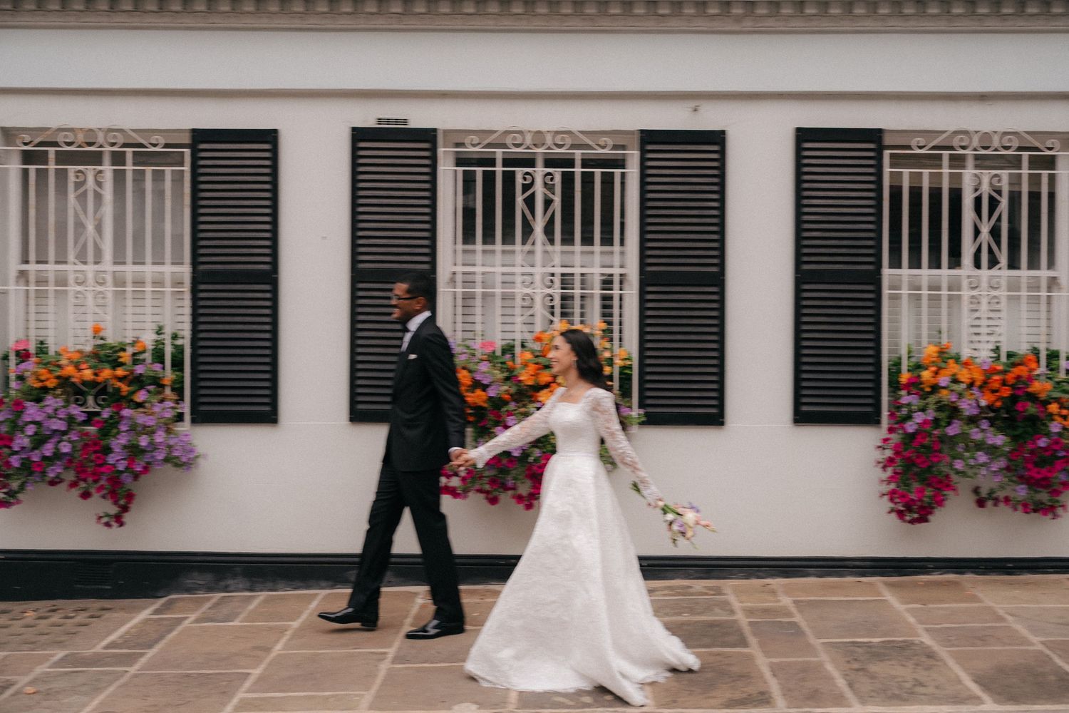 Elegant wedding portraits against white building with window boxes.