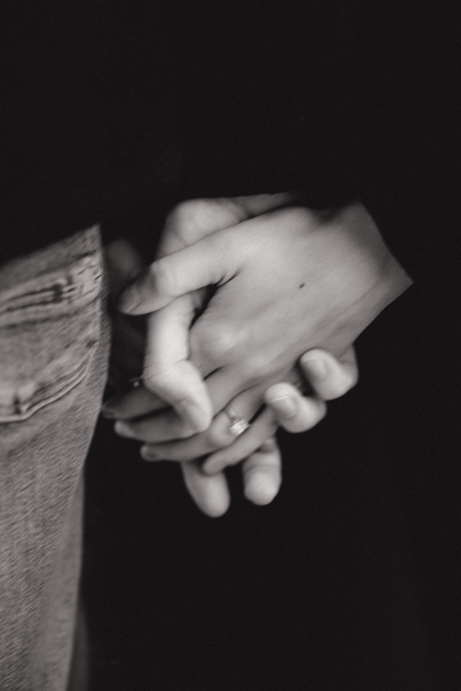 Black and white close-up of hands holding in intimate moment.