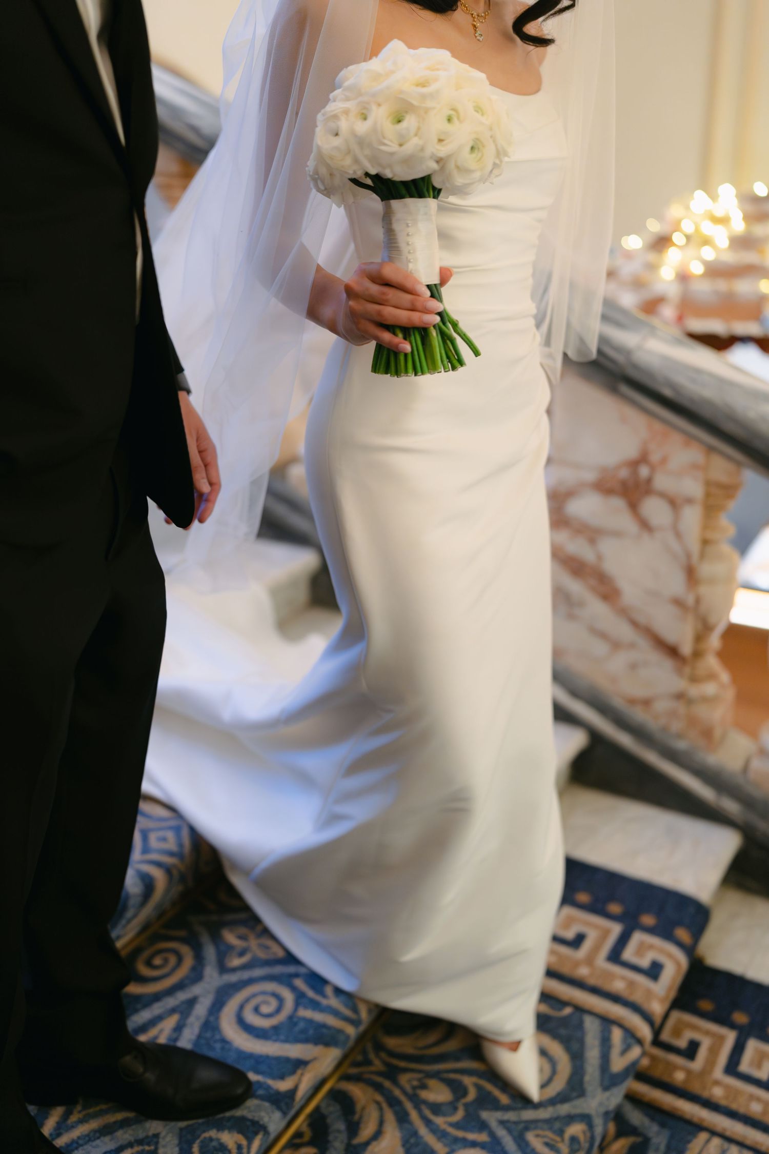 Bride in elegant white dress holding bouquet during wedding ceremony.
