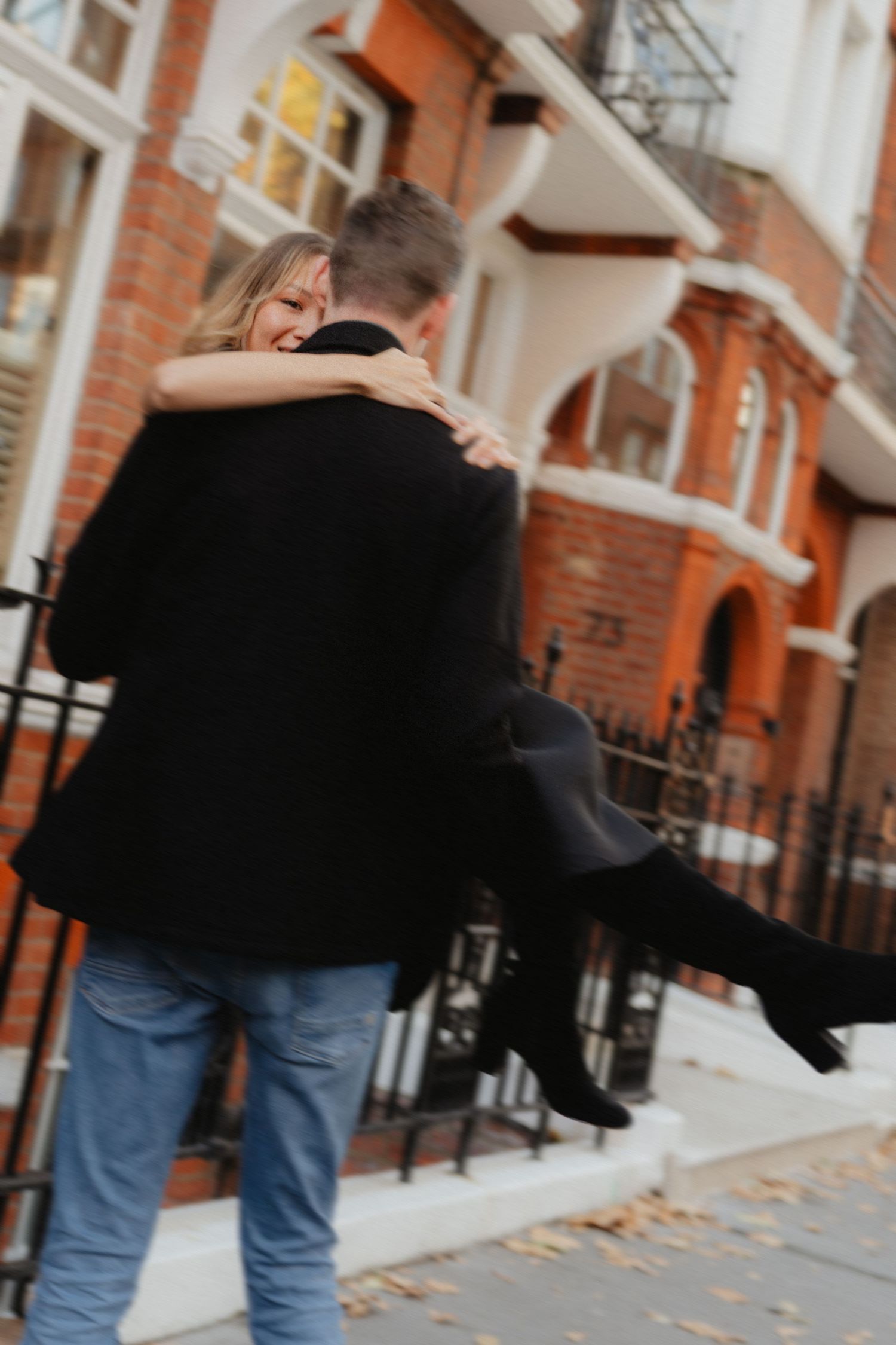 Couple walking together on a brick-lined street in autumn with fallen leaves.