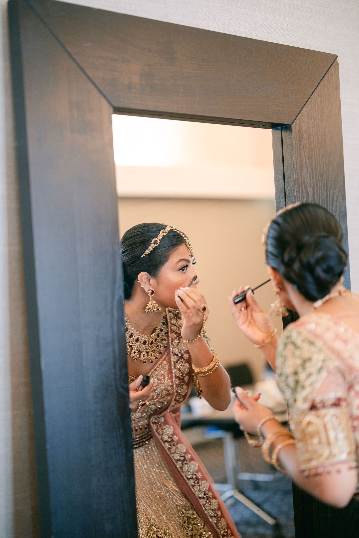 Makeup artist applying traditional Indian bridal makeup and adornments in an elegant preparation sequence.