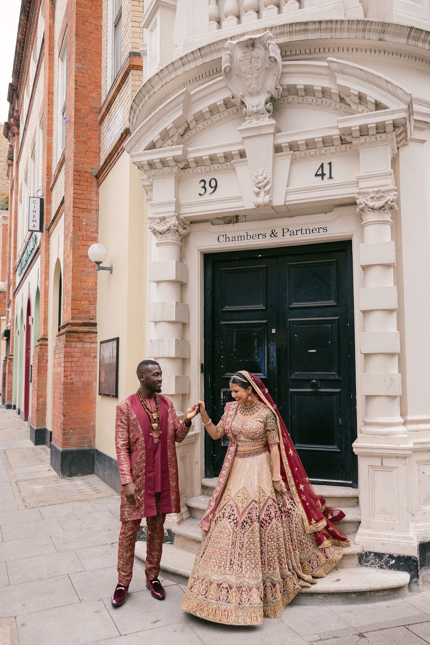 Elegant Indian wedding photoshoot outside historic London building with ornate architectural details.