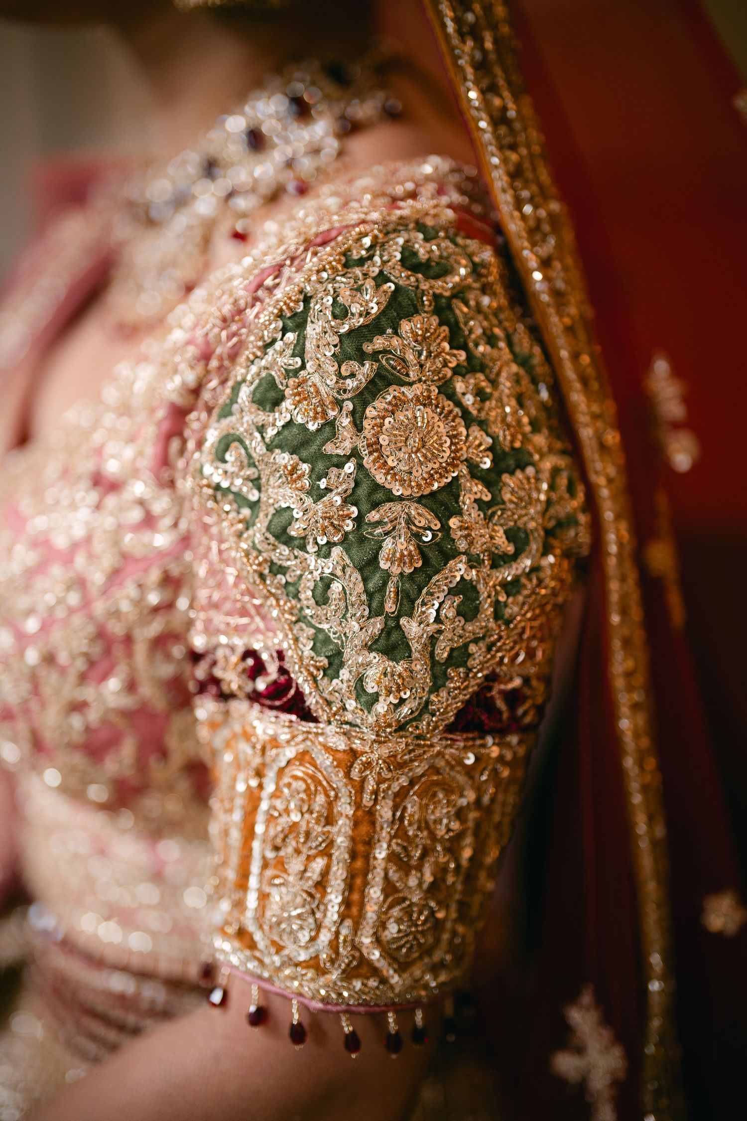 Intricate gold and green beaded embroidery detail on traditional South Asian bridal attire.
