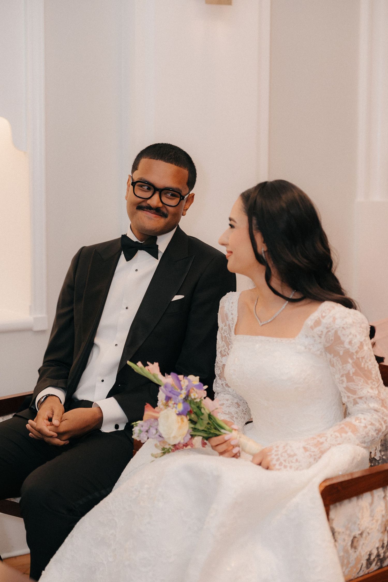 A couple shares an intimate moment while sitting together during their wedding celebration.