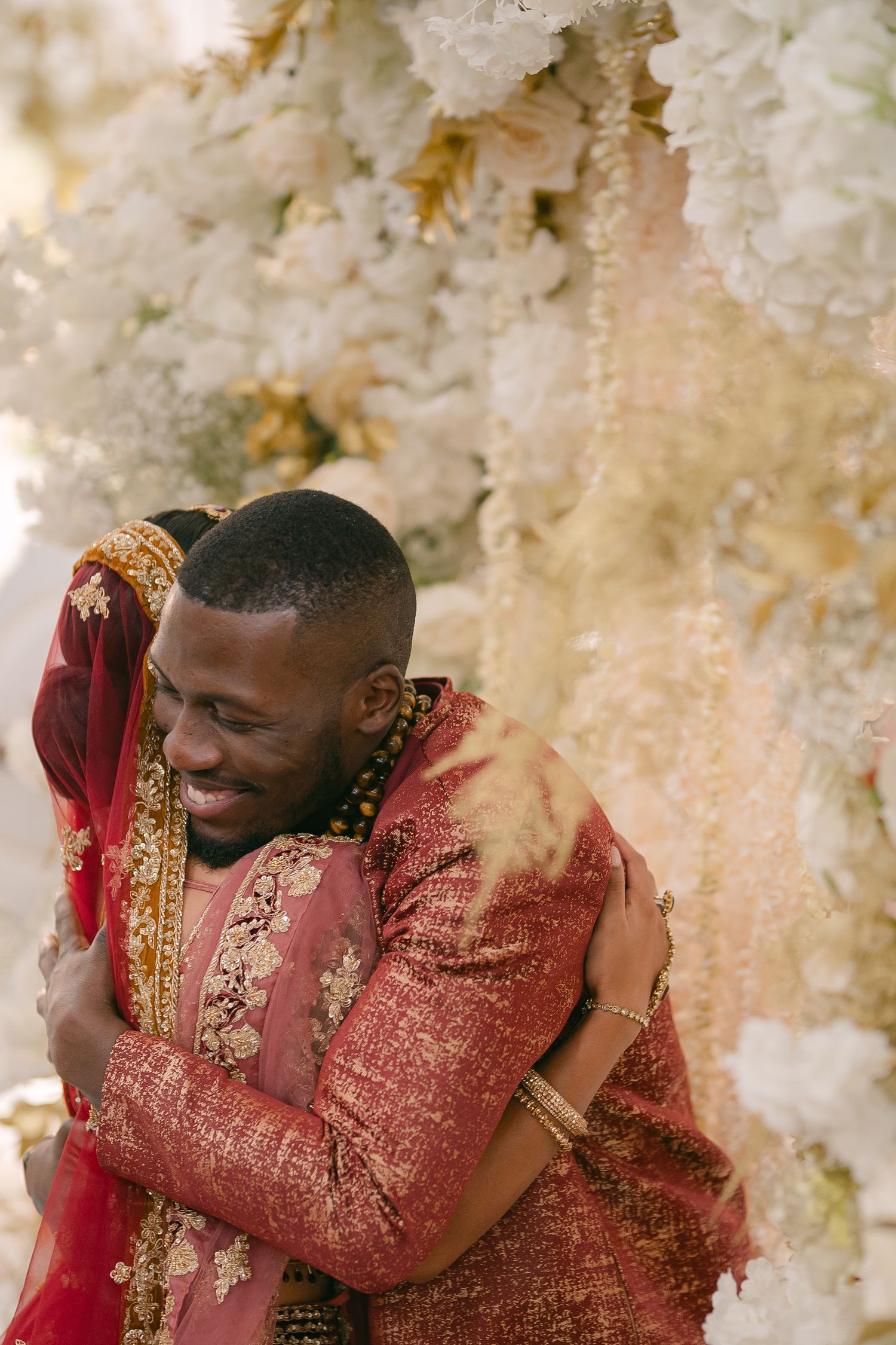 Emotional wedding moment captured against a backdrop of white floral decorations.