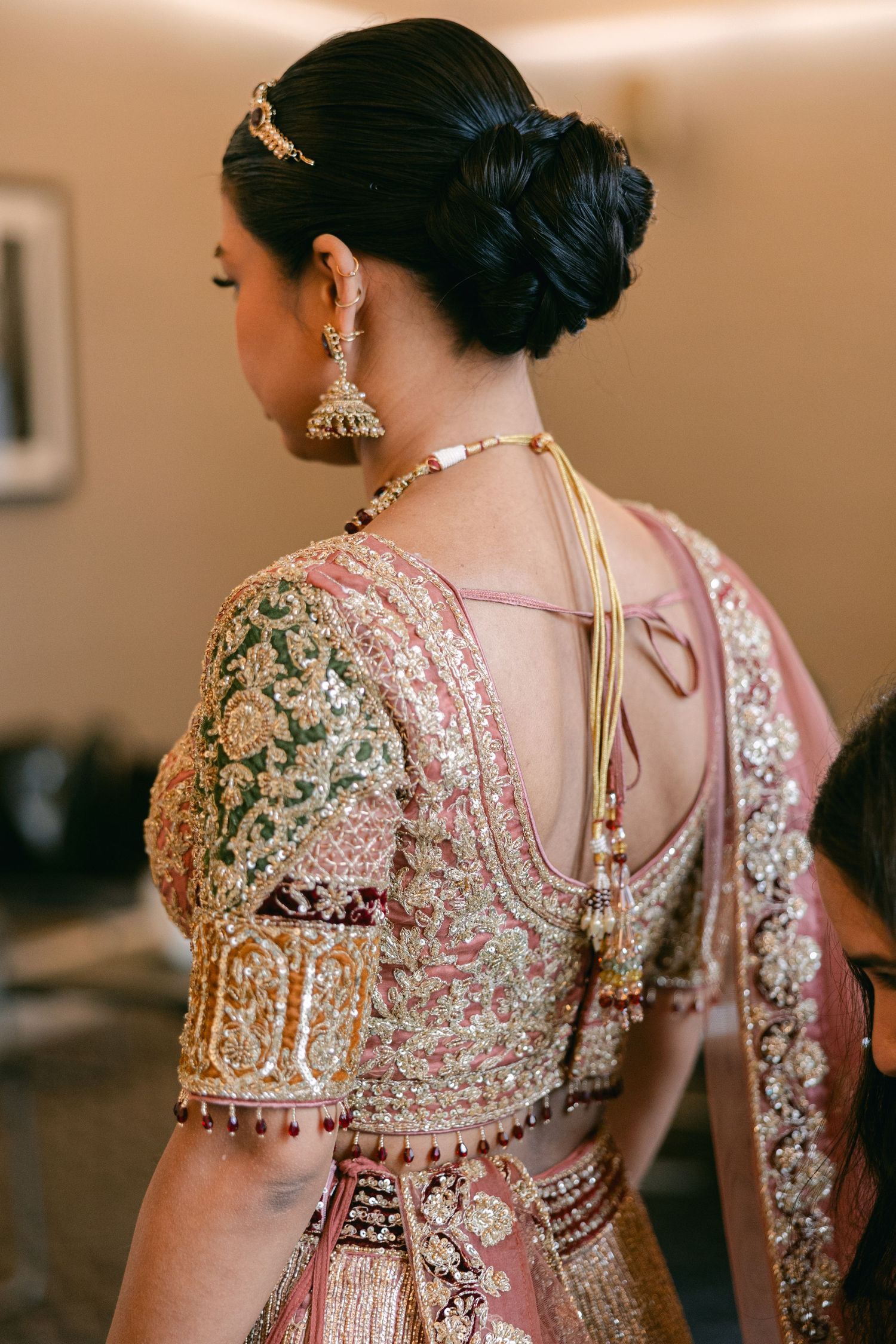 Detailed back view of pink and gold embellished South Asian bridal blouse with ornate beadwork.
