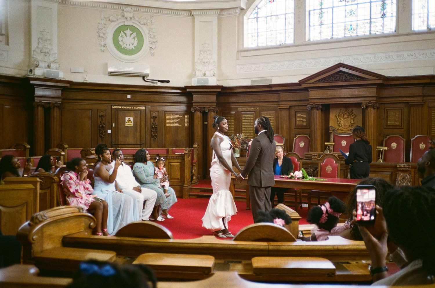 Wedding ceremony in a historic church with bride and groom at the altar surrounded by guests.