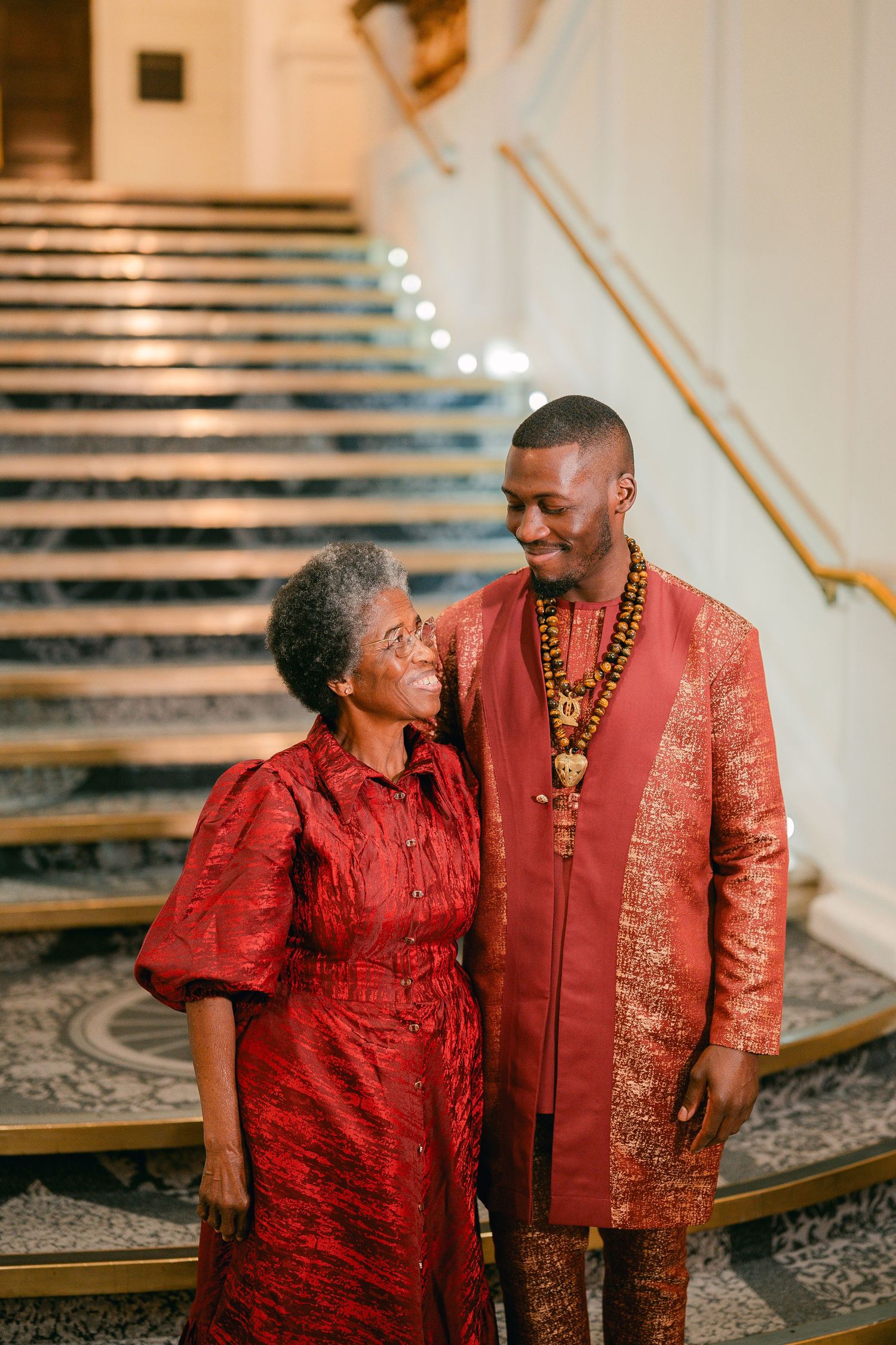 Mother and son sharing joyful moments in matching red outfits at a wedding celebration.