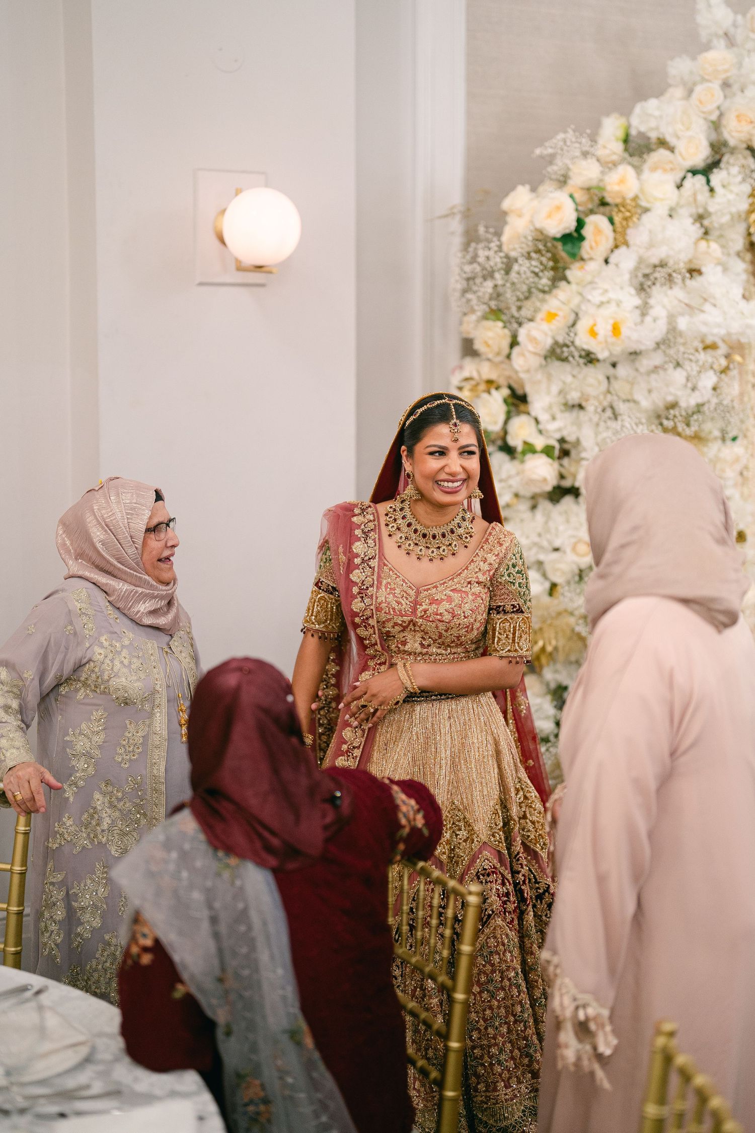 Wedding guests in traditional attire gathered around floral decorations at reception.