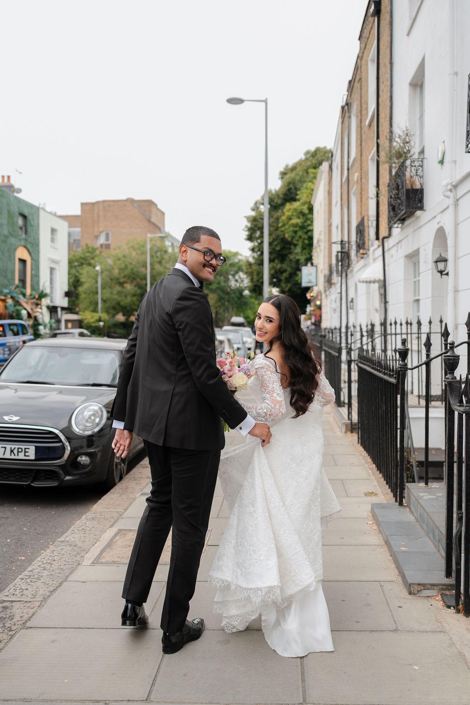 Newlyweds walking along a classic London street with white townhouses in the background.