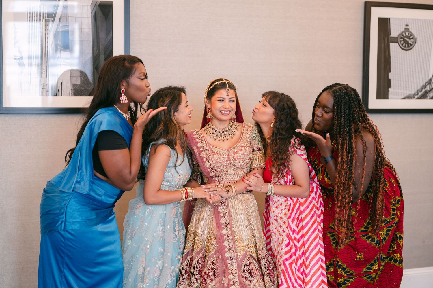 A group gathers in a bright indoor space wearing colorful traditional Indian attire and western clothing.