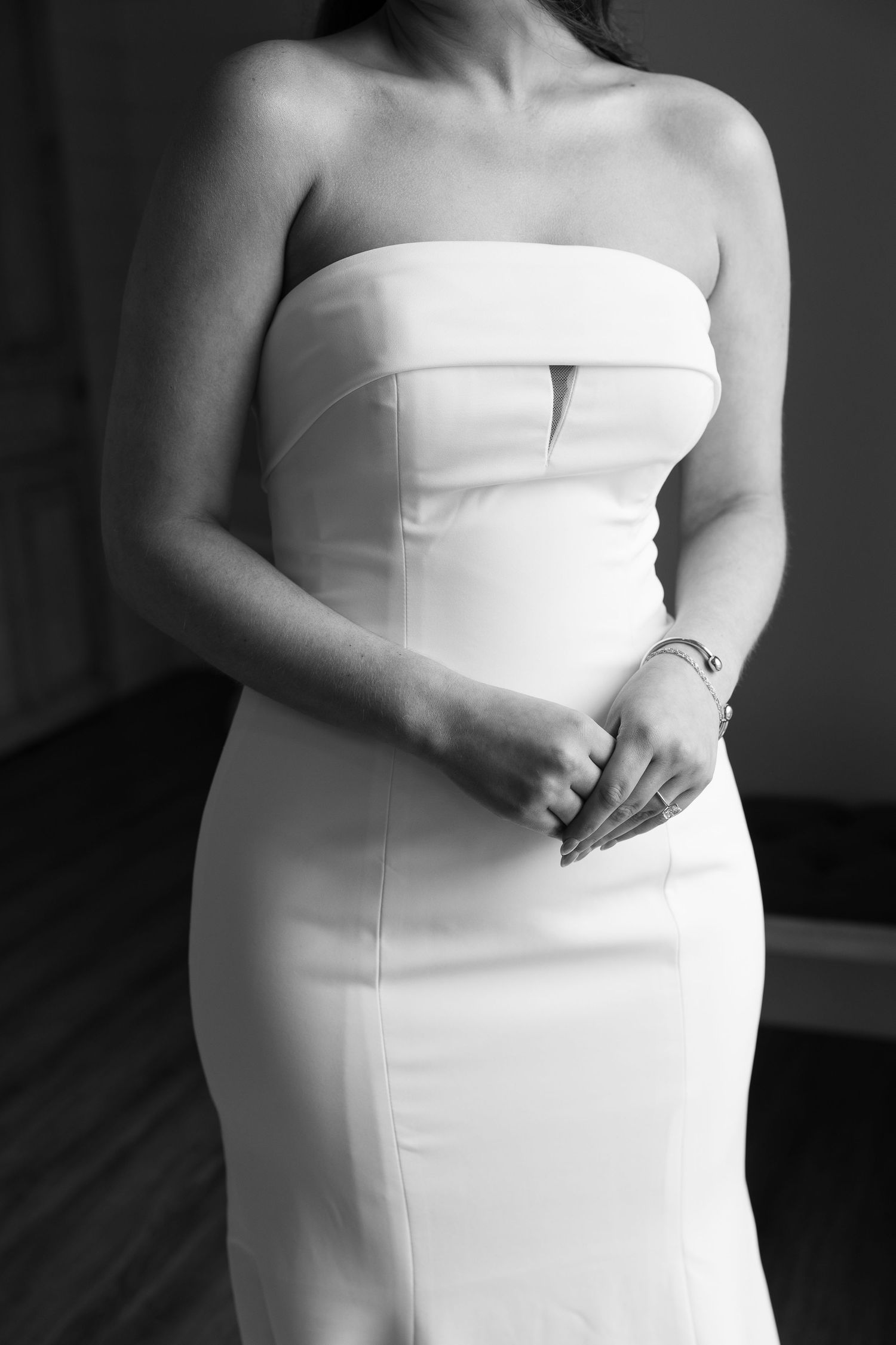 Black and white photo of bride in sleek strapless white wedding gown with structured bodice.