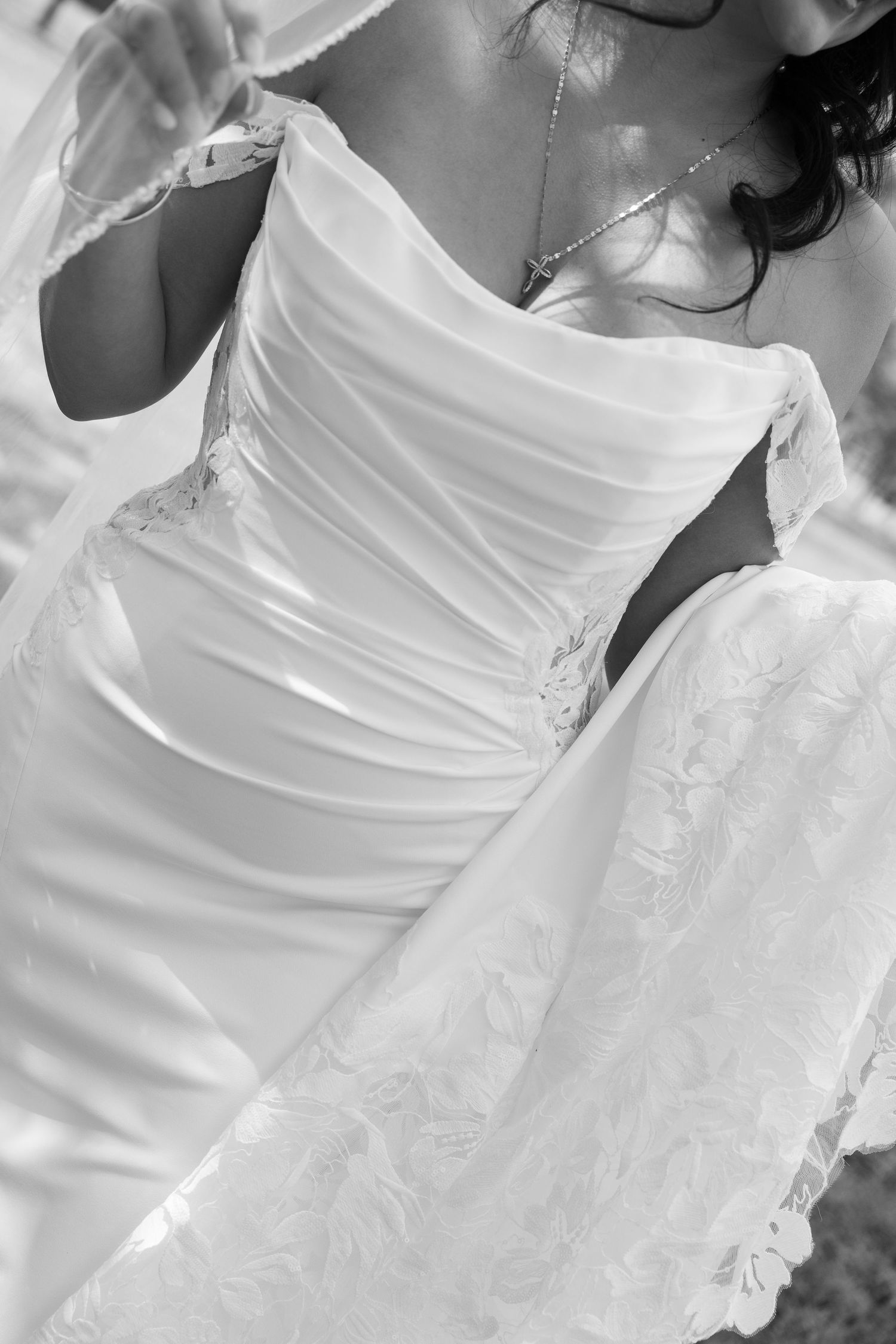 Black and white close-up of a bride in a strapless ruched wedding gown with lace detail.