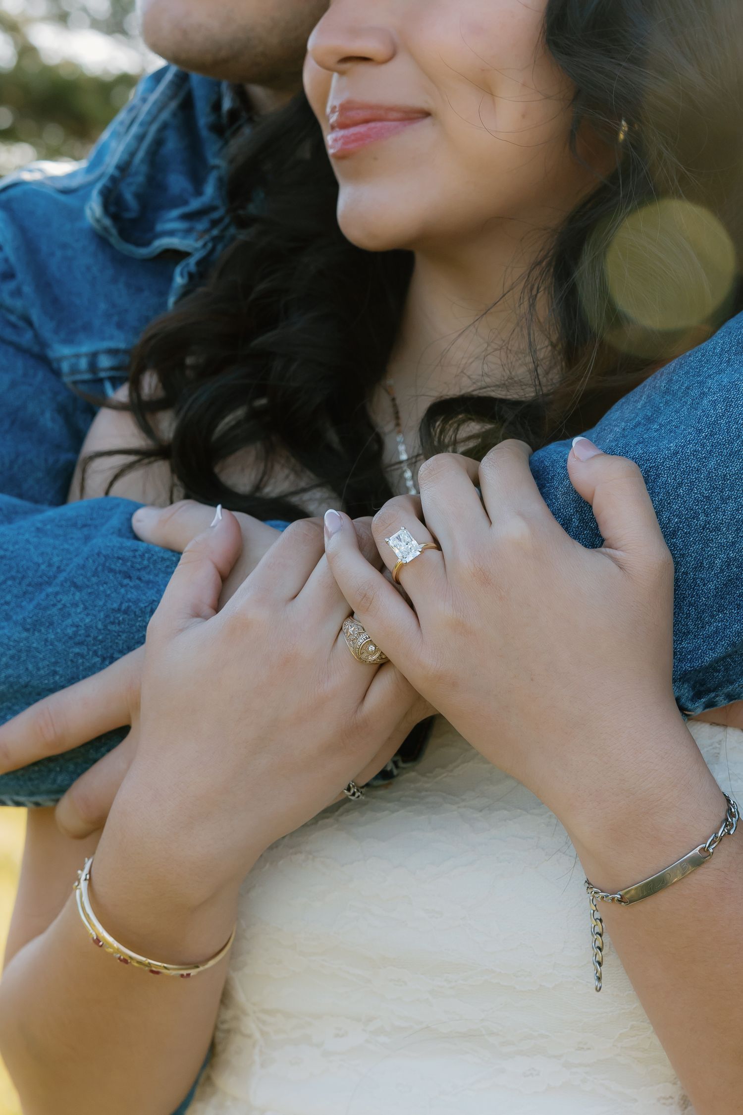 Close-up of couple holding hands showing engagement ring and bracelets.
