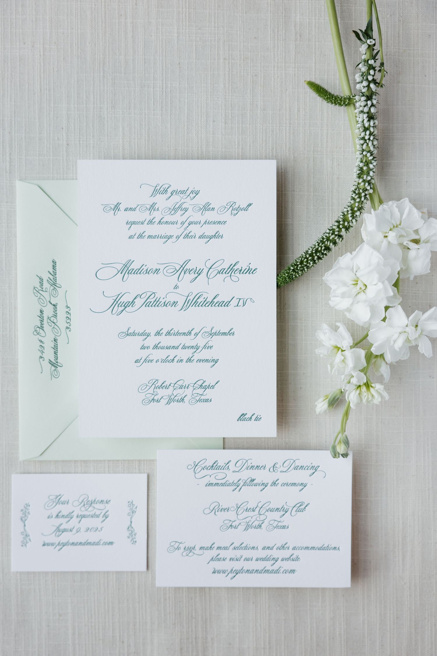 Elegant wedding invitation suite in teal script on white cardstock with mint envelope and white floral accents.