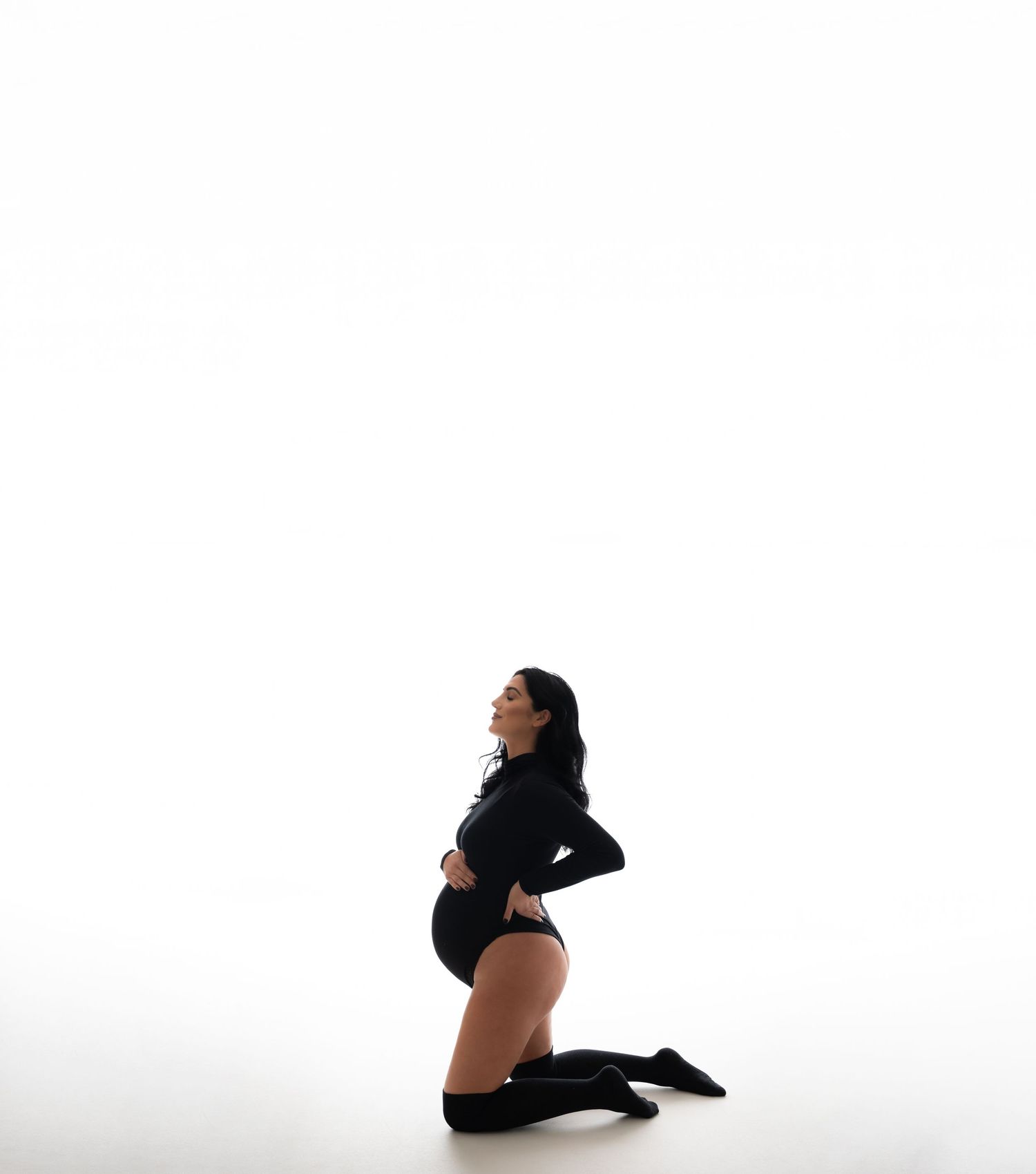 Silhouetted figure poses in black outfit against white background.