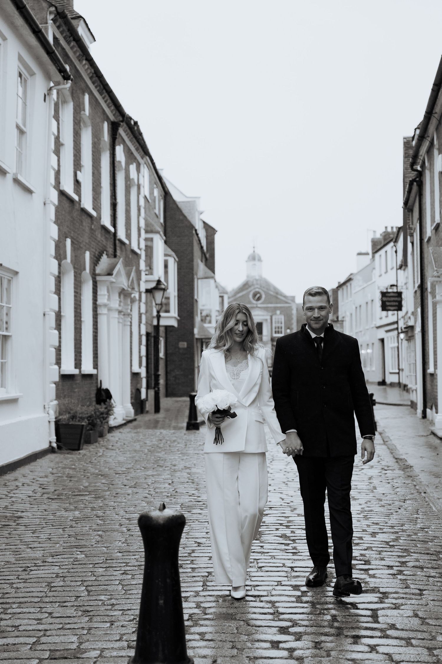Black and white photos of a couple walking down a cobblestone street in poole wedding photographer guildhall poole