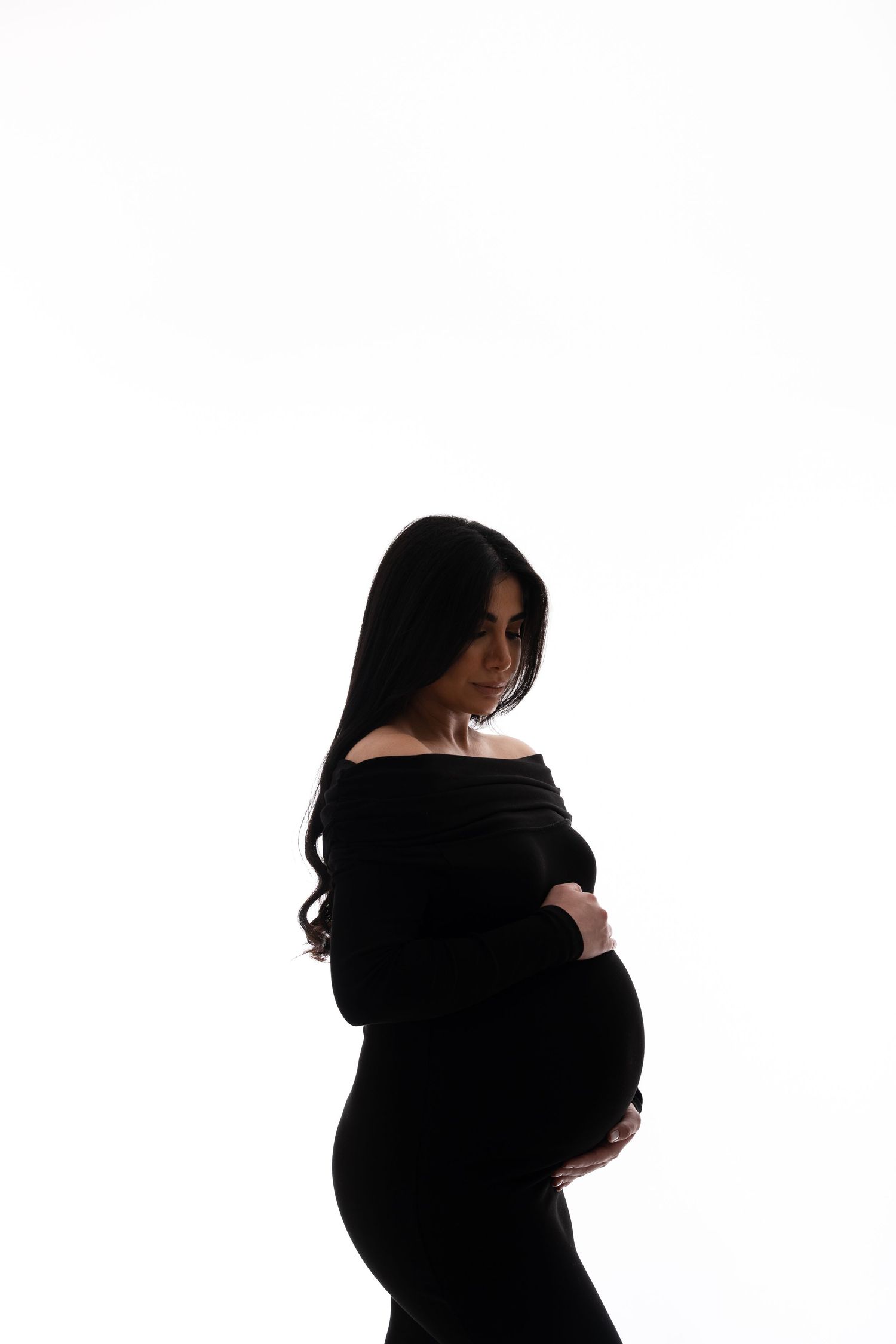 Elegant black maternity photos showing silhouette against white background.