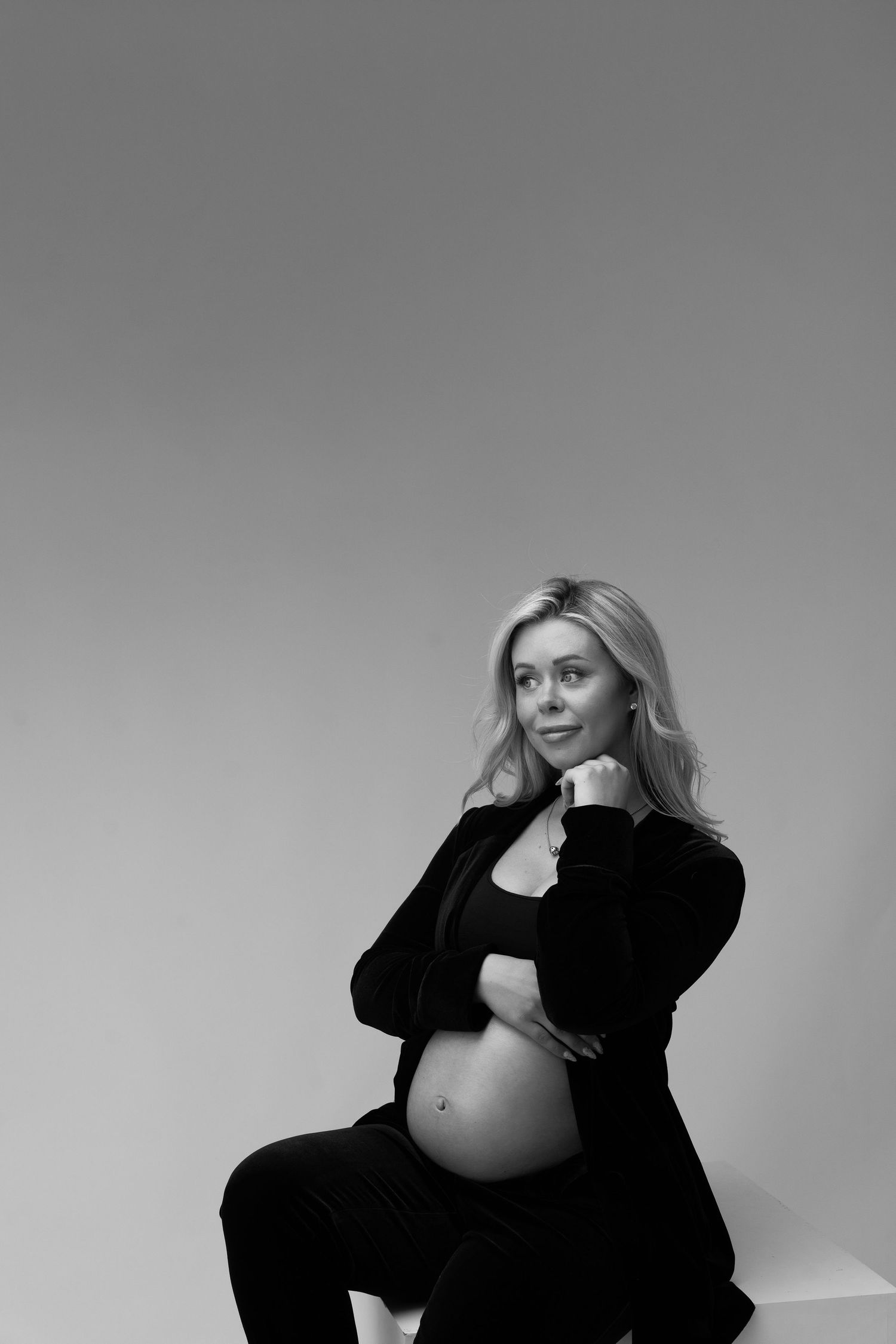 Dramatic black and white maternity portraits showing pregnant woman in dark clothing.