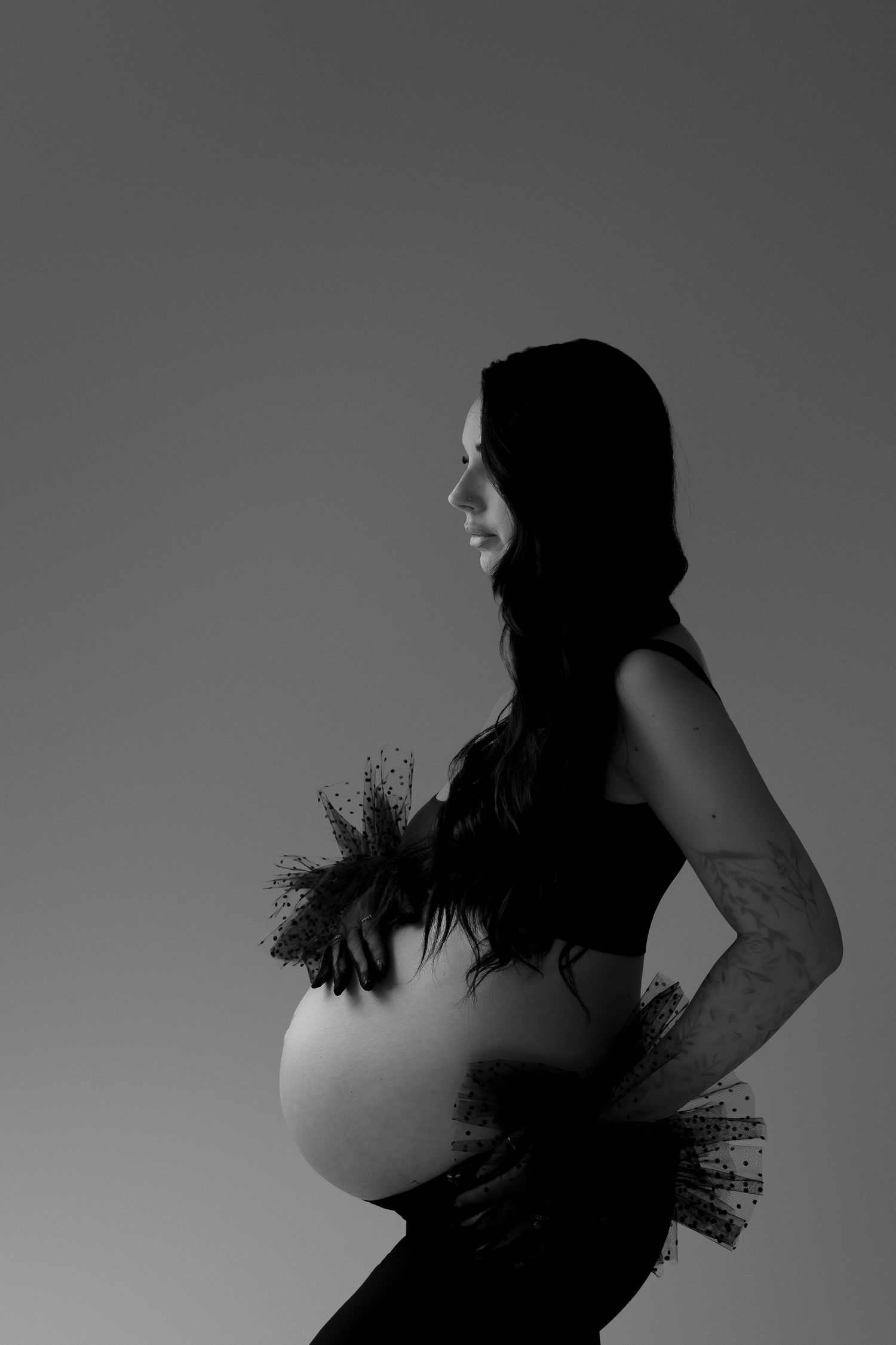 Black and white silhouette of pregnant figure with tulle details.