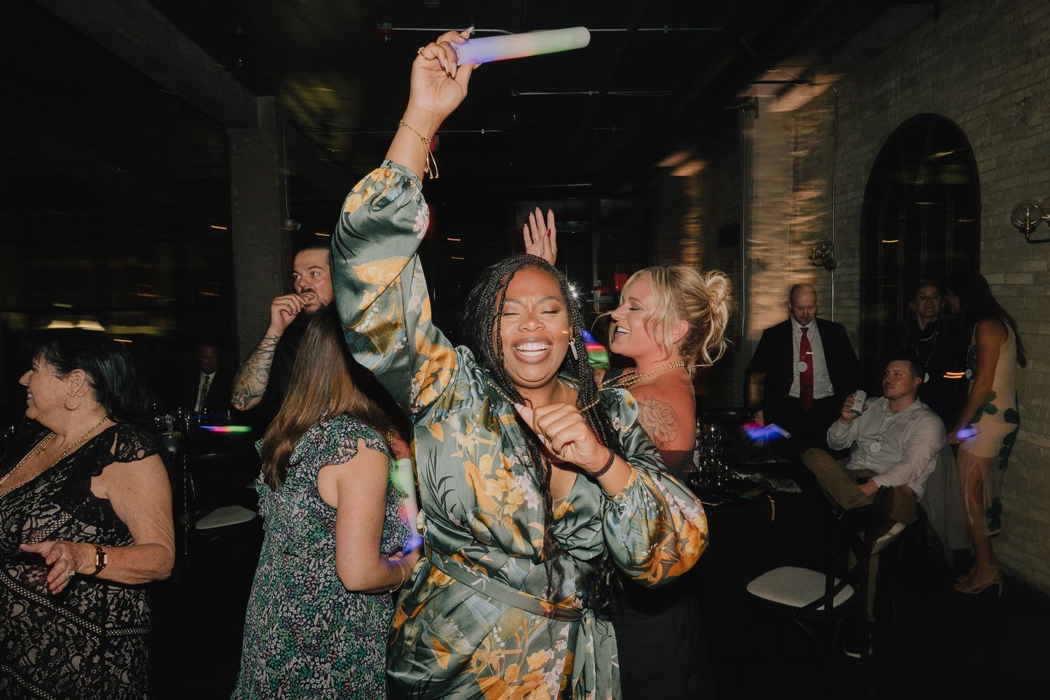 A woman with a smile dances with her hand up at a wedding.