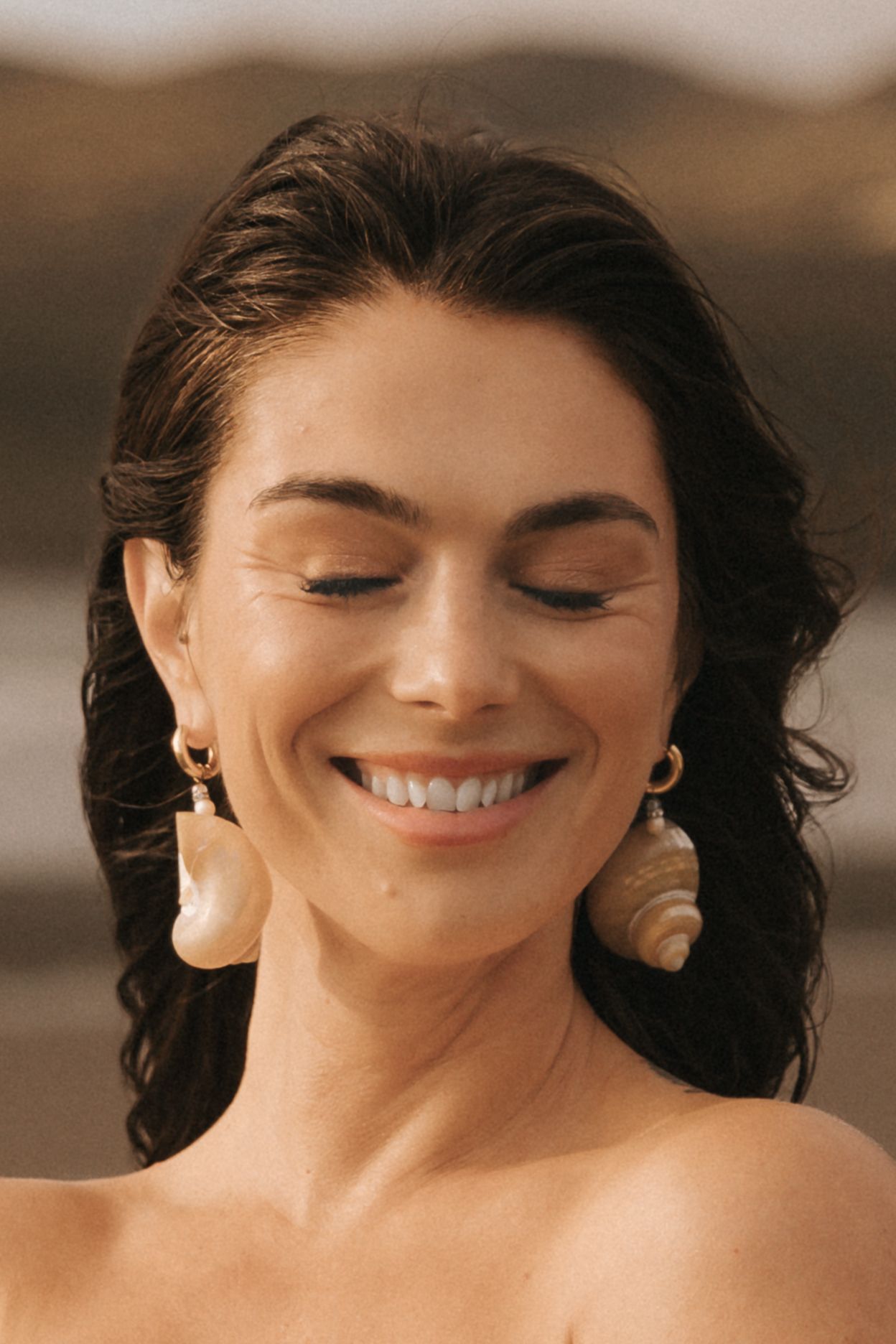 Close-up portrait showing joyful expression and dark wavy hair.