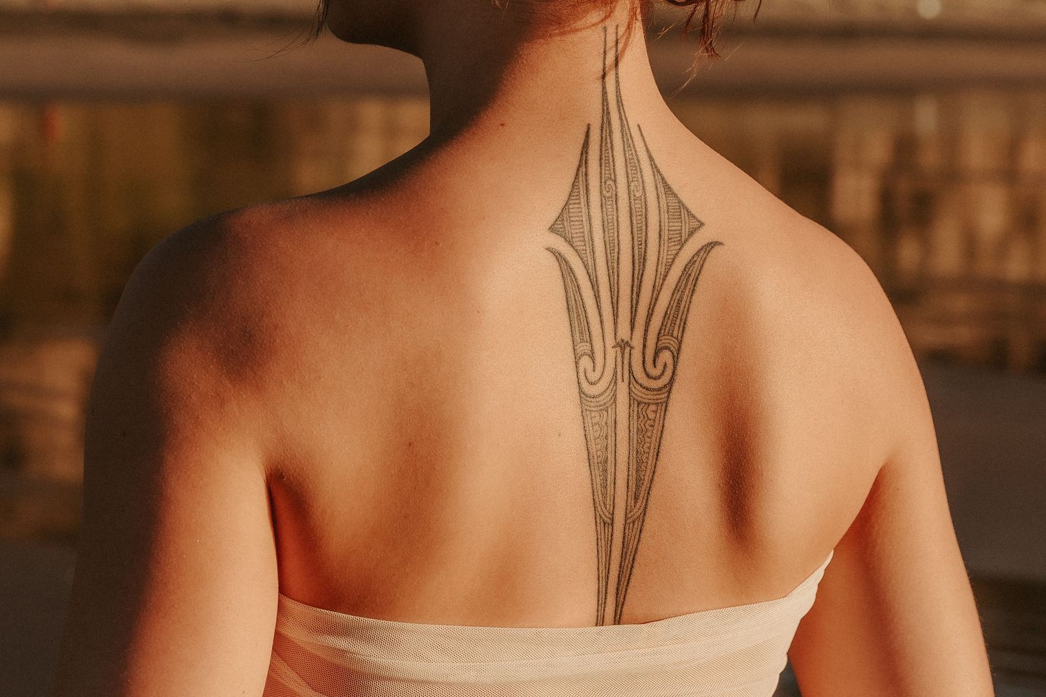 Back view showing intricate tribal tattoo design on person's spine.