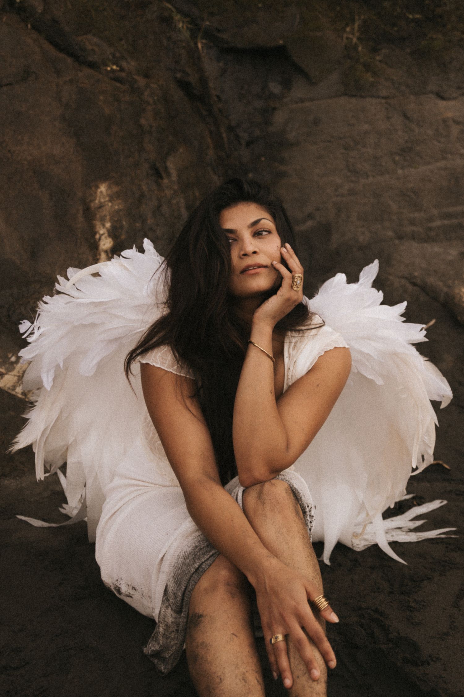 Artistic portrait series showing figure in white tulle dress against dark stone background.
