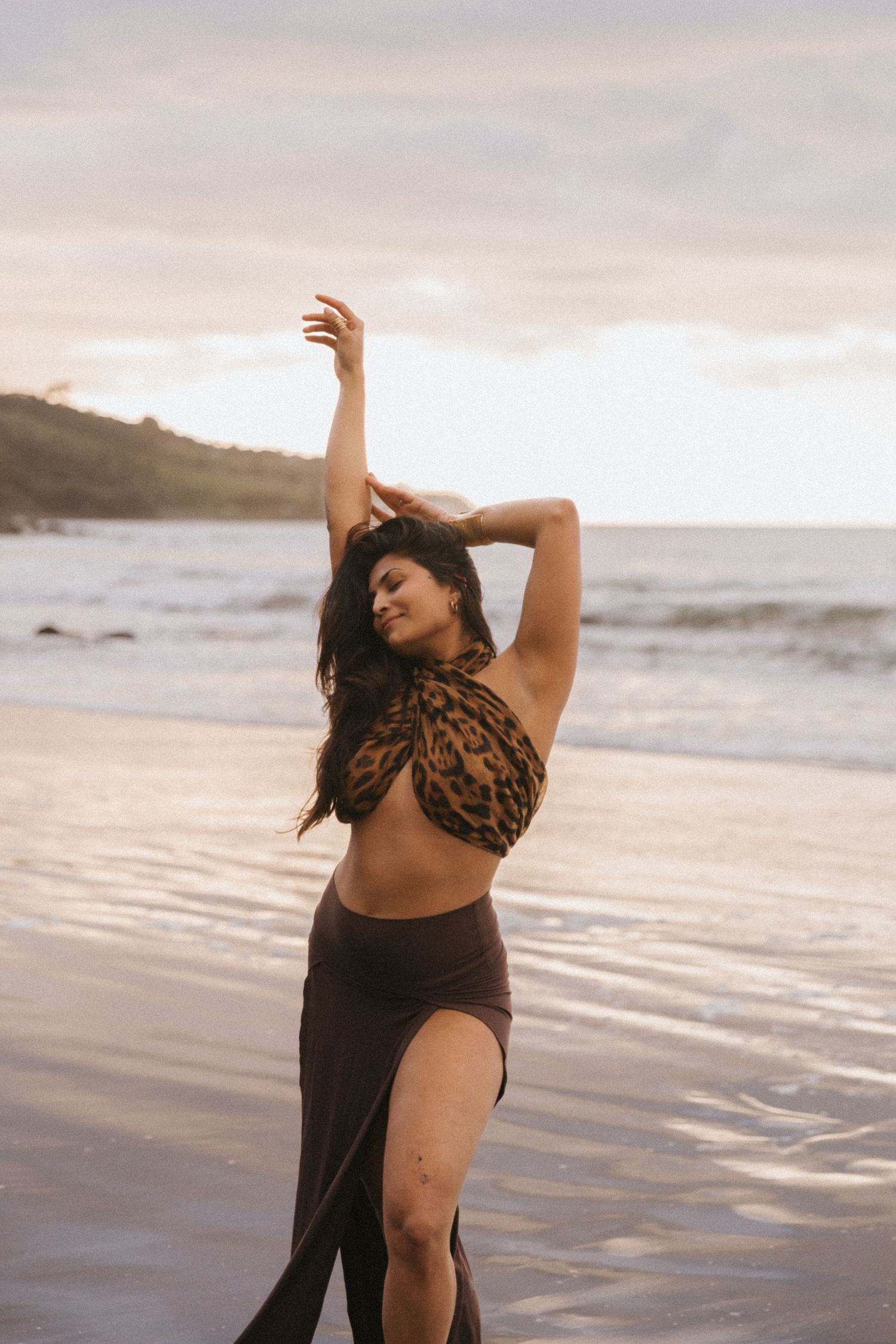 A dancer performs graceful movements on a misty beach at sunset, expressing artistic motion through dance.