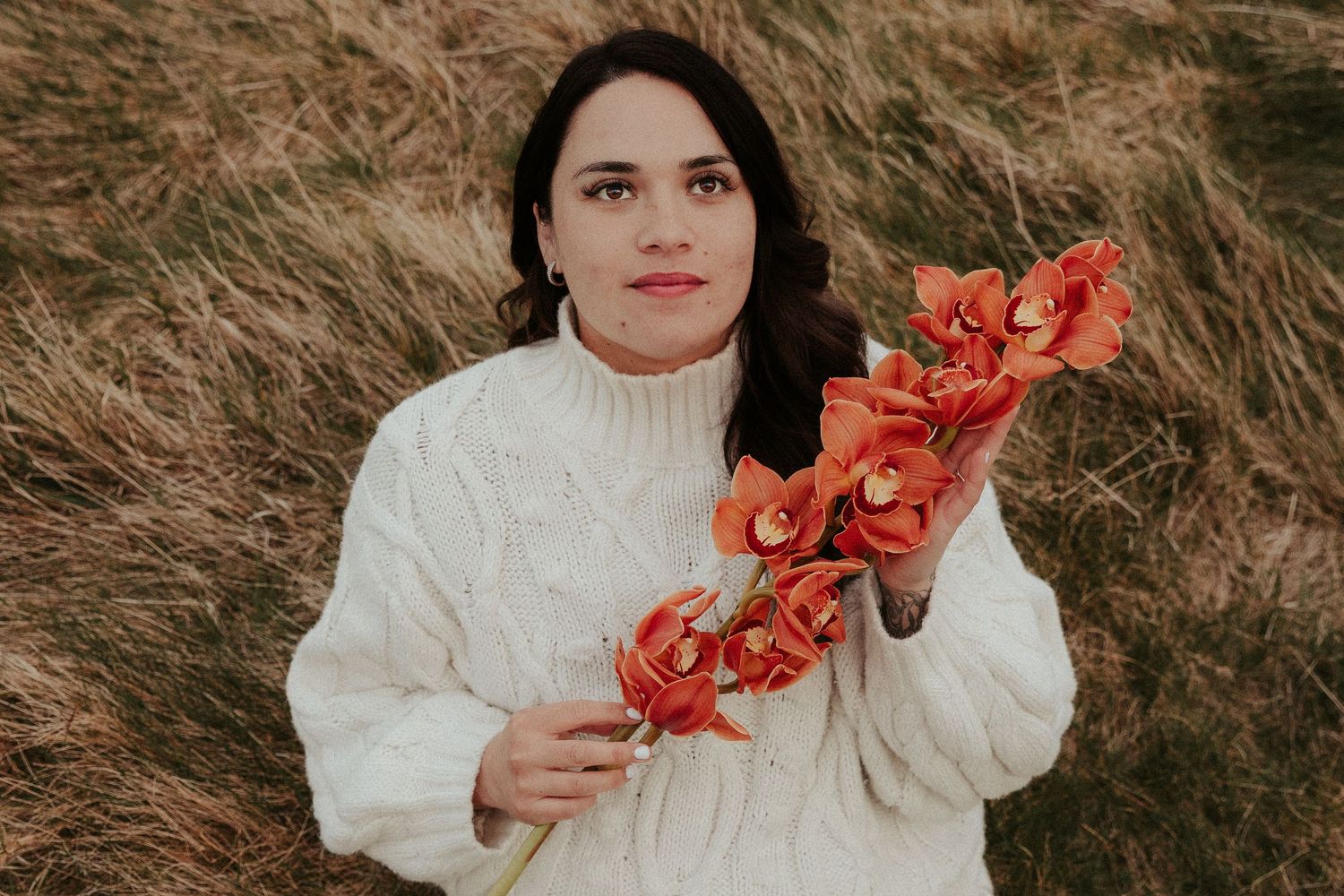 Elegant portrait series featuring red orchids and white sweater against natural backdrop.