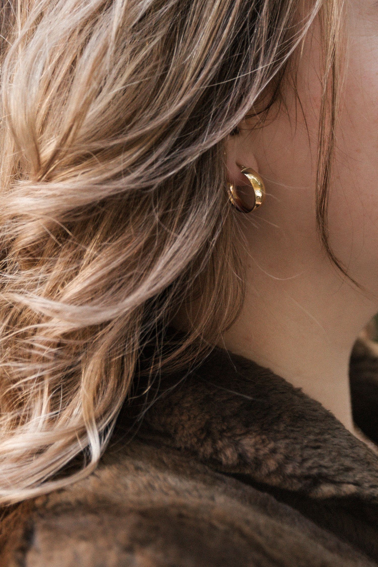 Close-up detail shot of blonde hair texture and dark fabric in natural lighting.