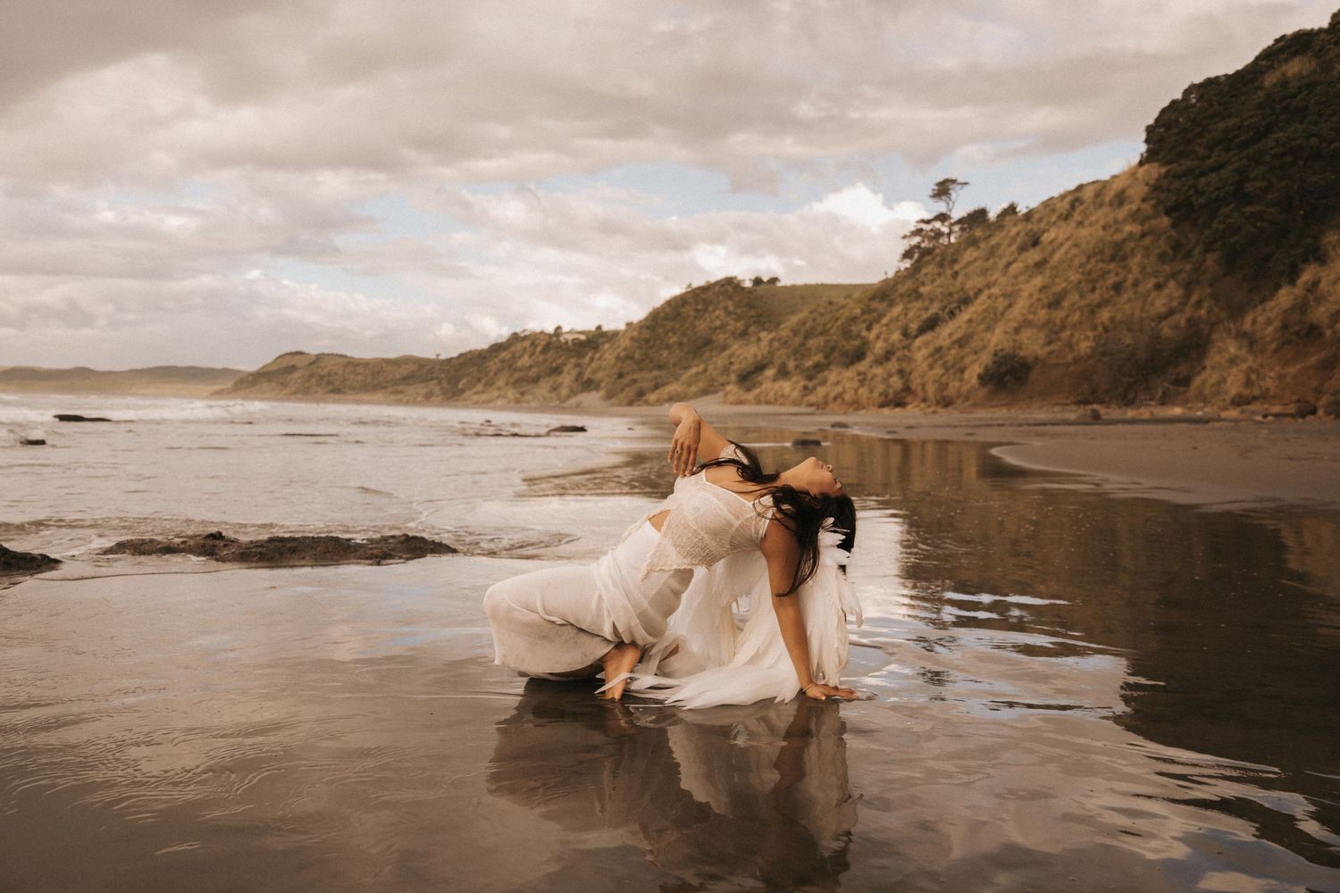 A romantic couple shares intimate moments on a misty beach with dramatic cliffs and coastline in the background.