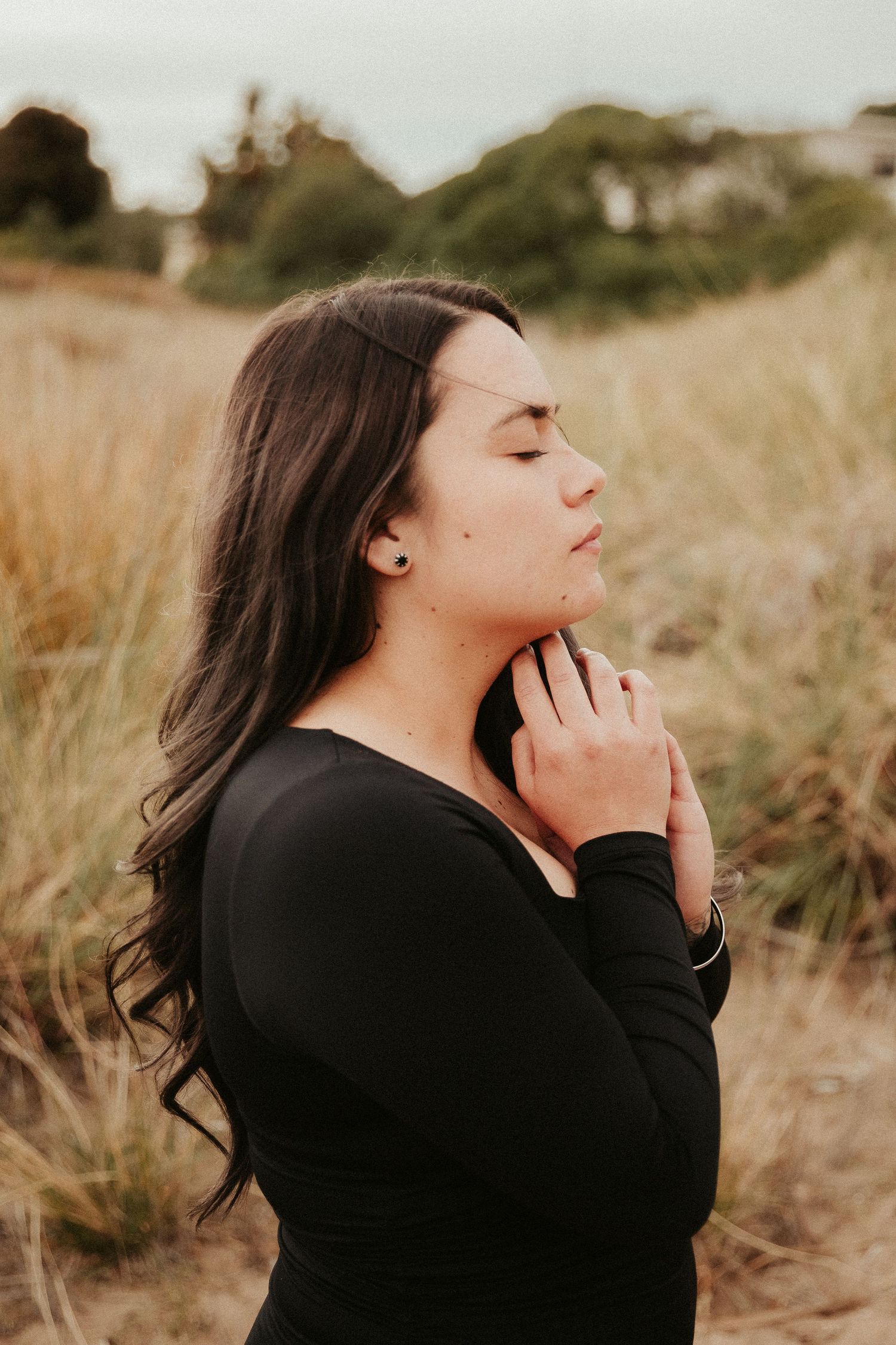 Artistic portrait in a field with soft golden light and tall grass.