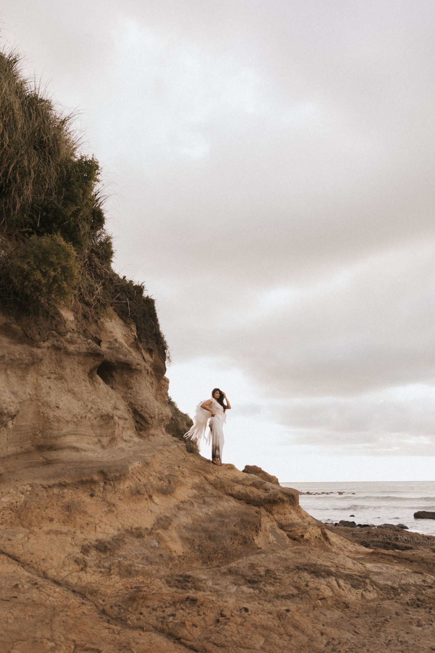 A series of images showing figures standing on coastal cliffs overlooking a rocky beach under an overcast sky.