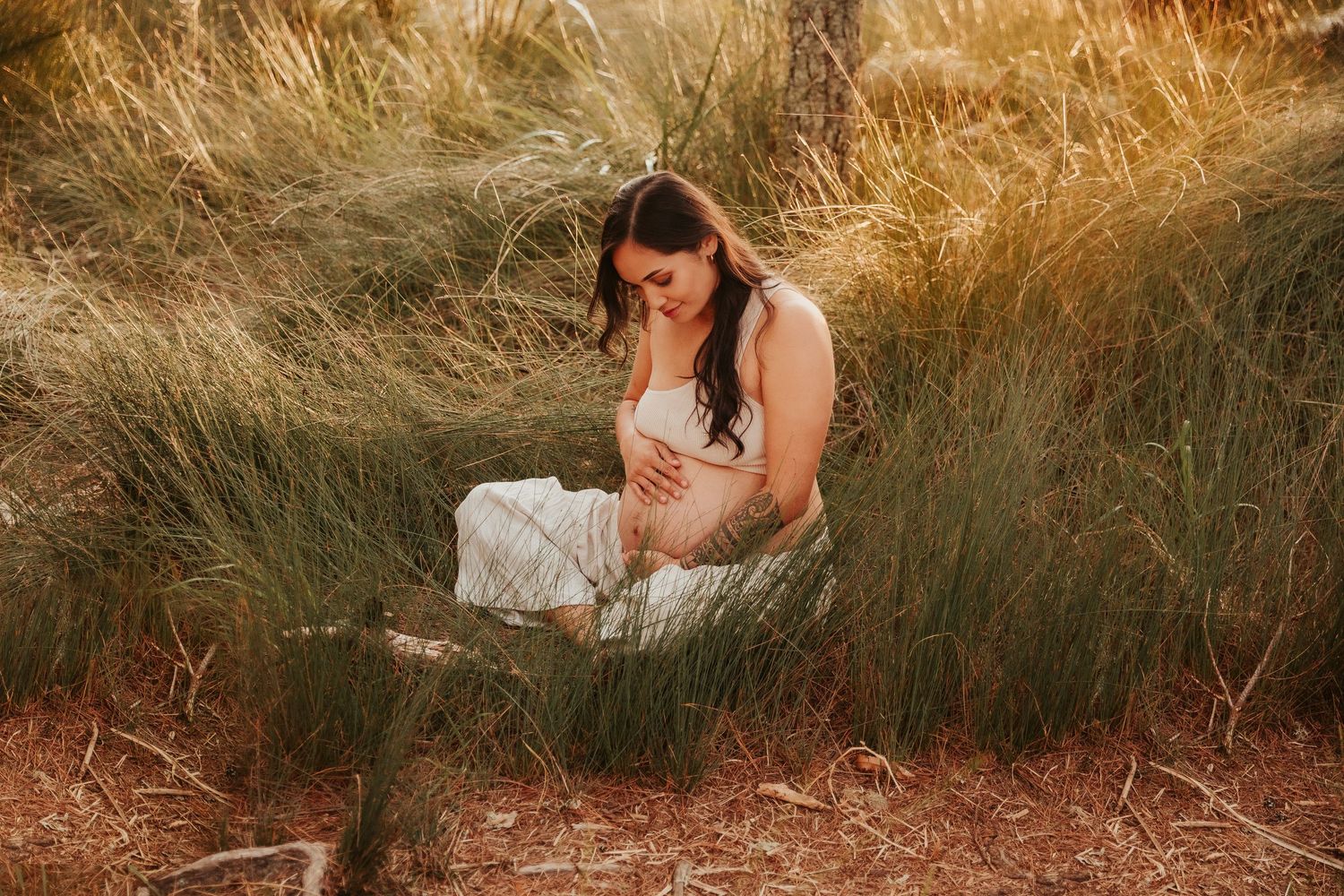 Artistic portrait session among golden dried grass and natural coastal vegetation.