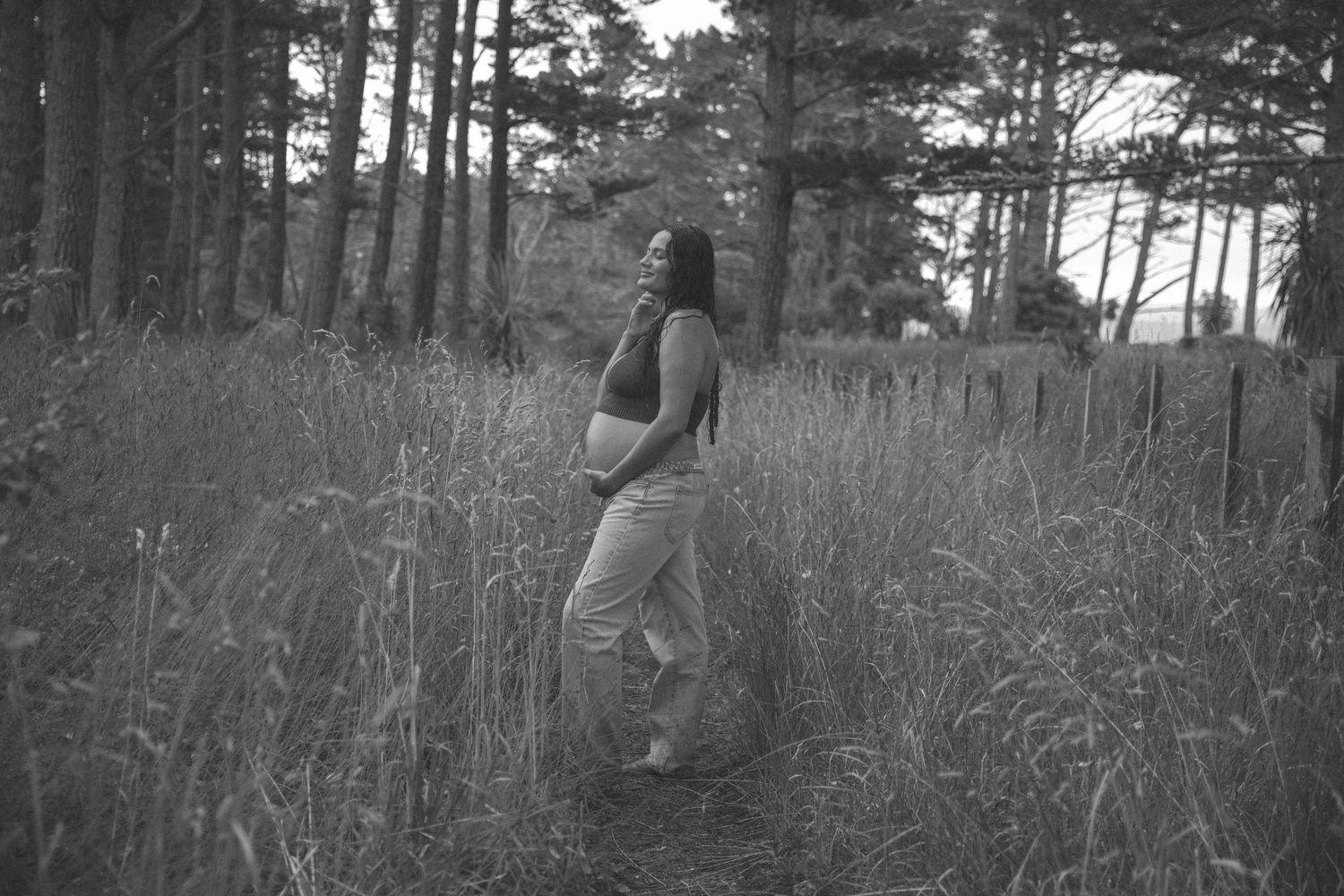 Artistic black and white photo of someone walking through a pine forest.