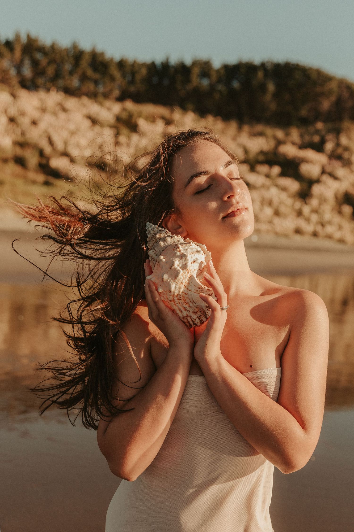 Artistic beach maternity photos with windswept hair and golden hour lighting.