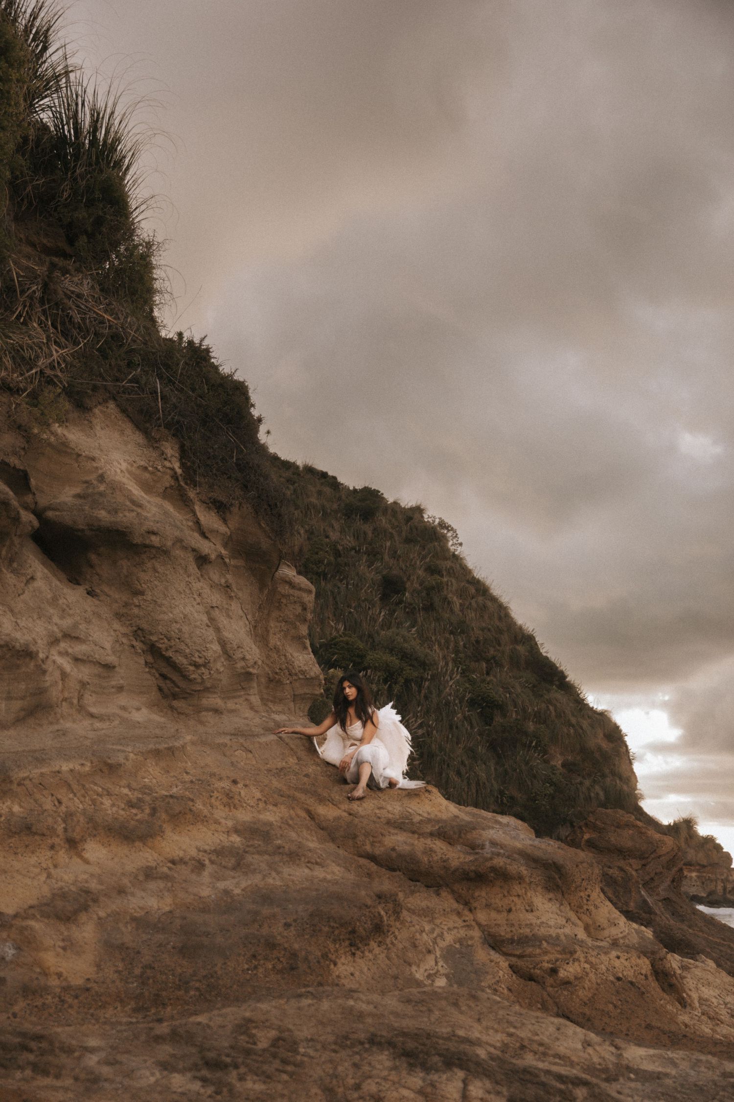 Dramatic series of sepia-toned coastal cliff photographs showing two people sitting together against a moody sky.