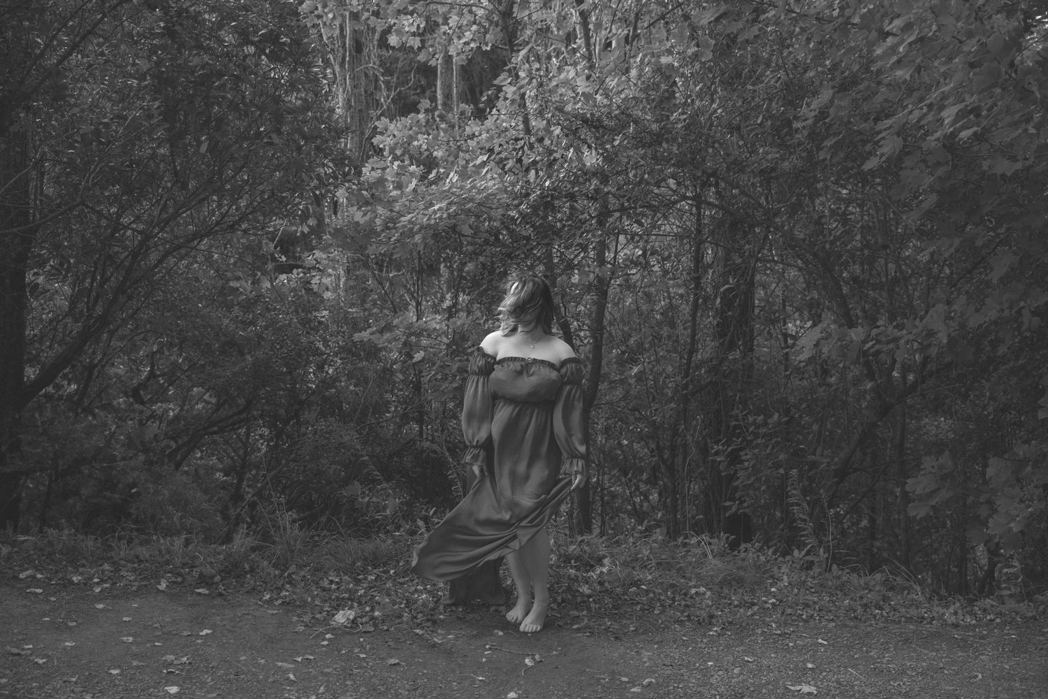 Artistic outdoor portrait session in a moody forest setting with dramatic lighting and natural scenery.