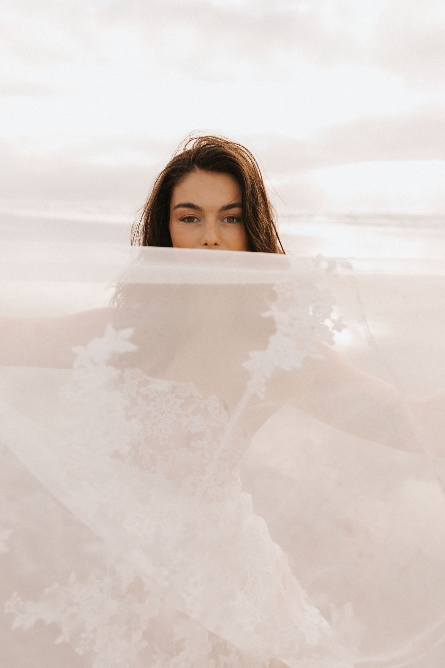Ethereal beach photography with flowing white fabric and soft natural lighting.