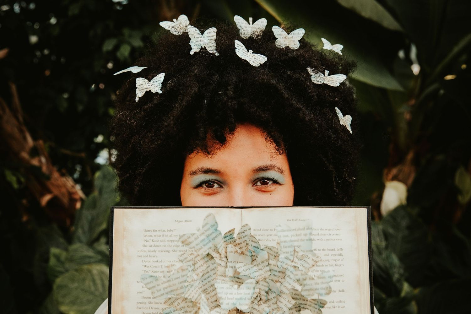 Artistic portrait with white paper butterflies and handwritten pages creating a whimsical scene.