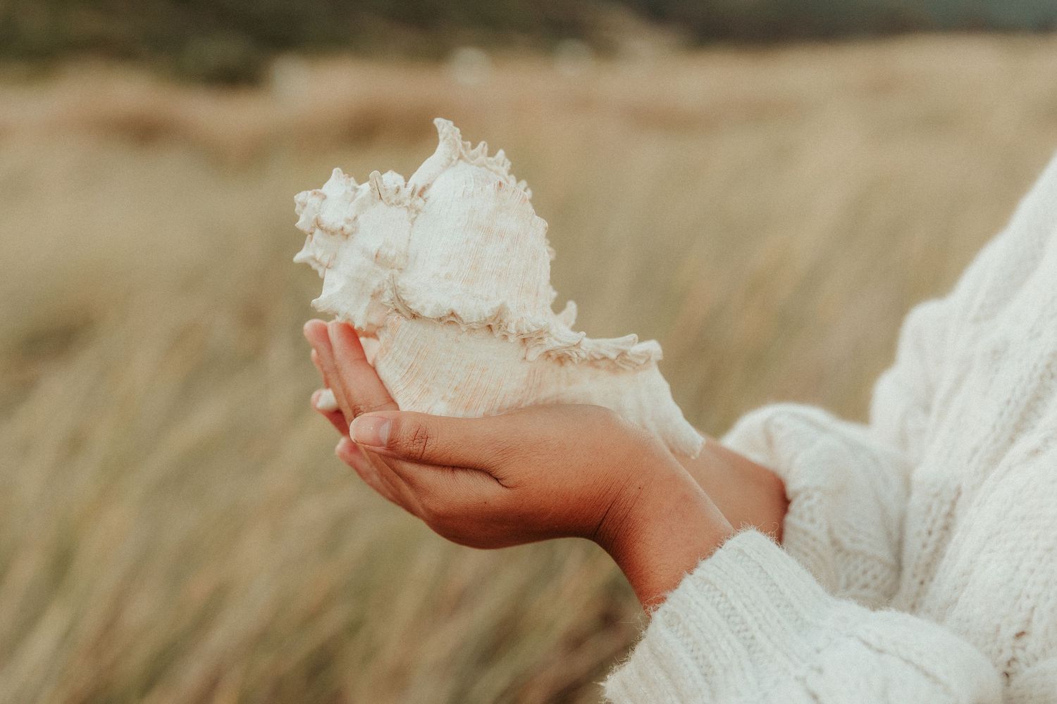 Bare feet resting on sandy ground with delicate white lace dress fabric.