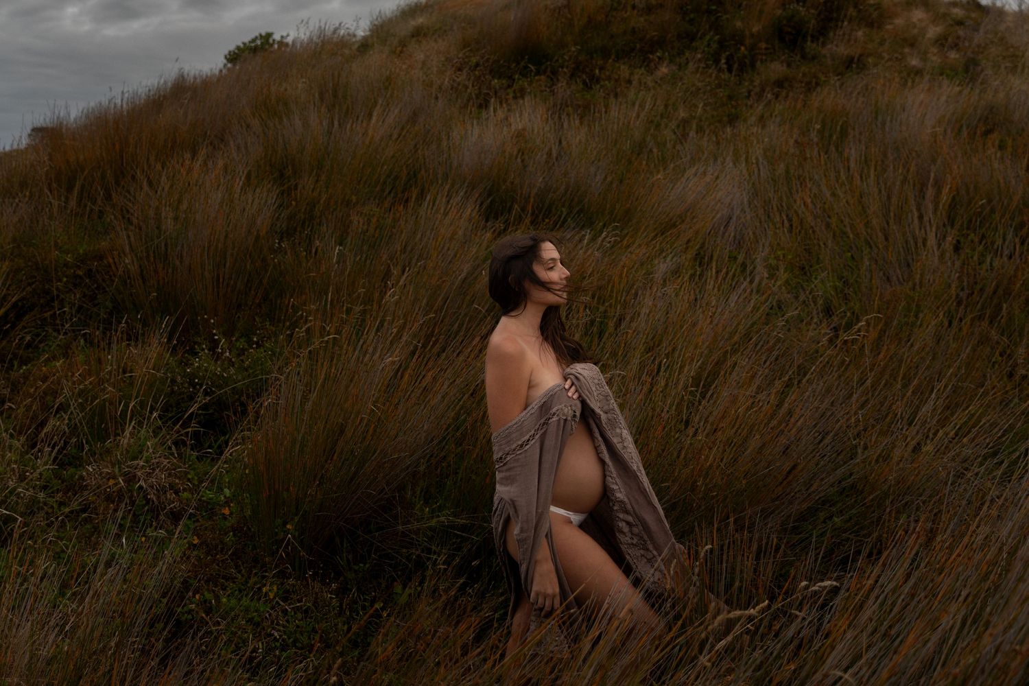 Dramatic portrait session in golden grass field during sunset.