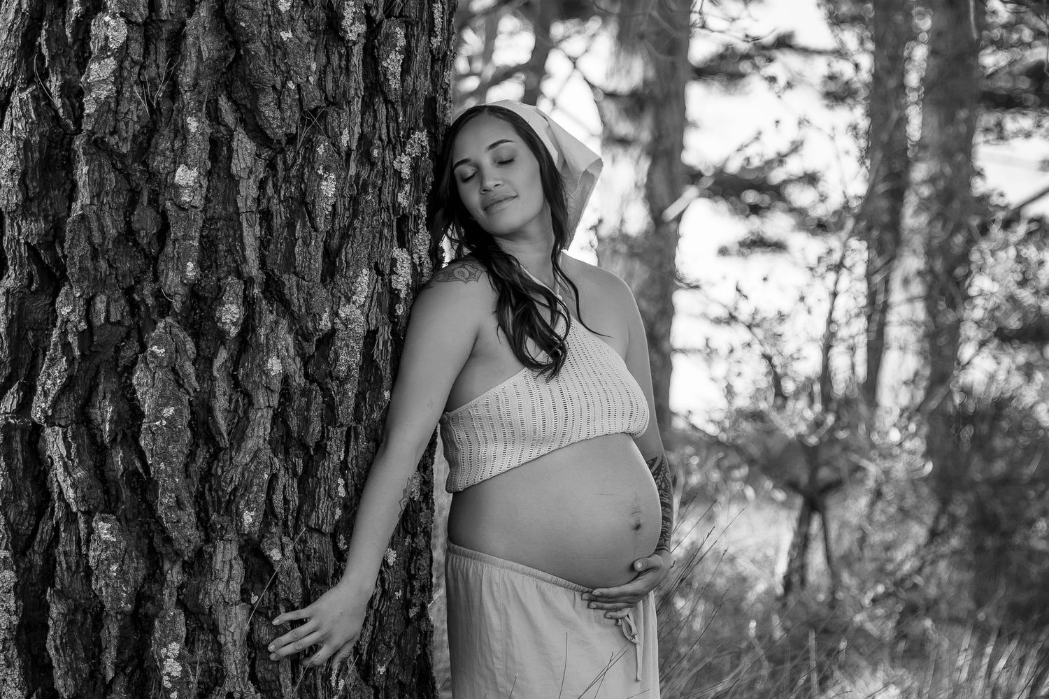 Natural outdoor portrait among tall pine trees in soft lighting.
