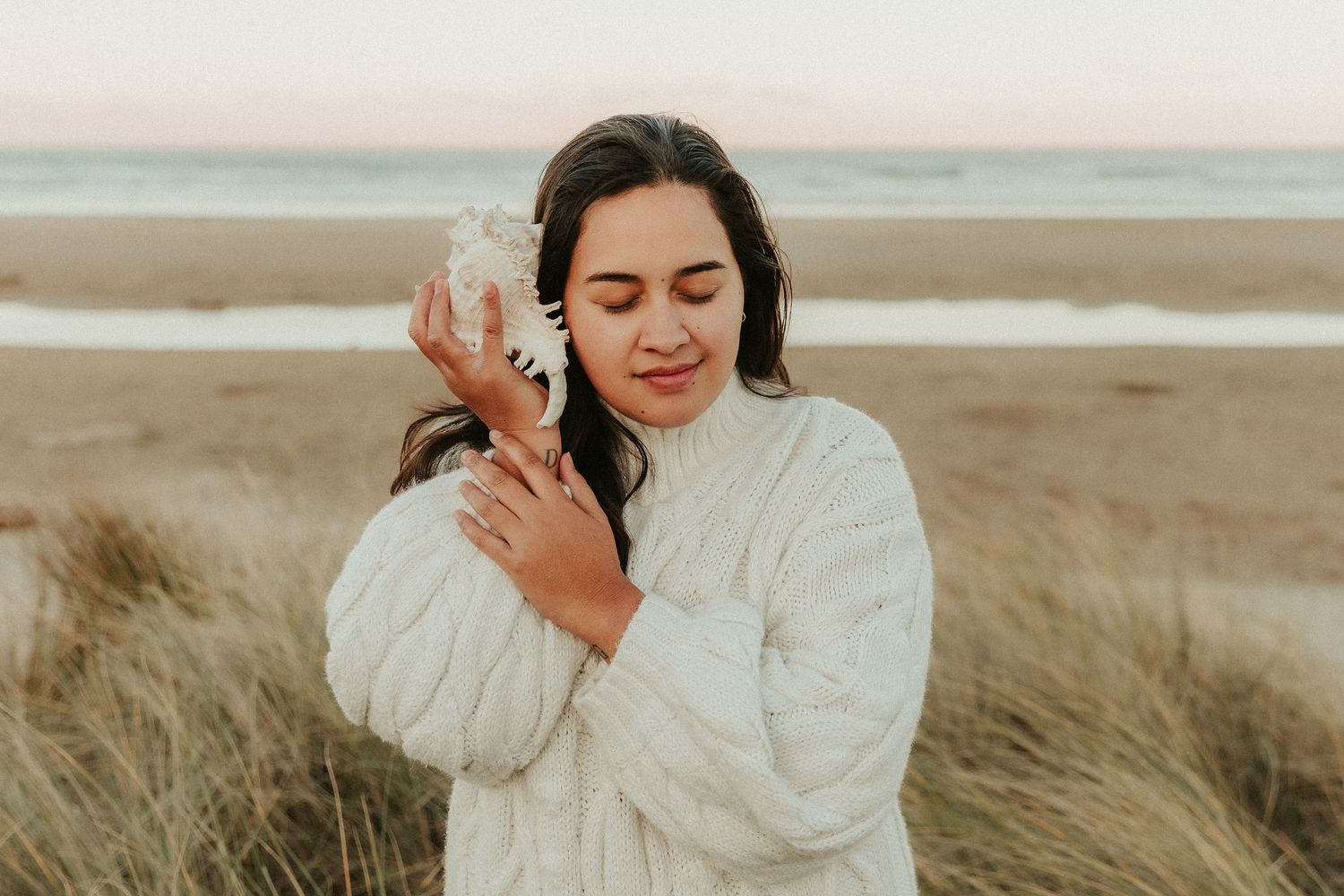 A dreamy coastal scene with beach grass swaying in the breeze against a soft sky.