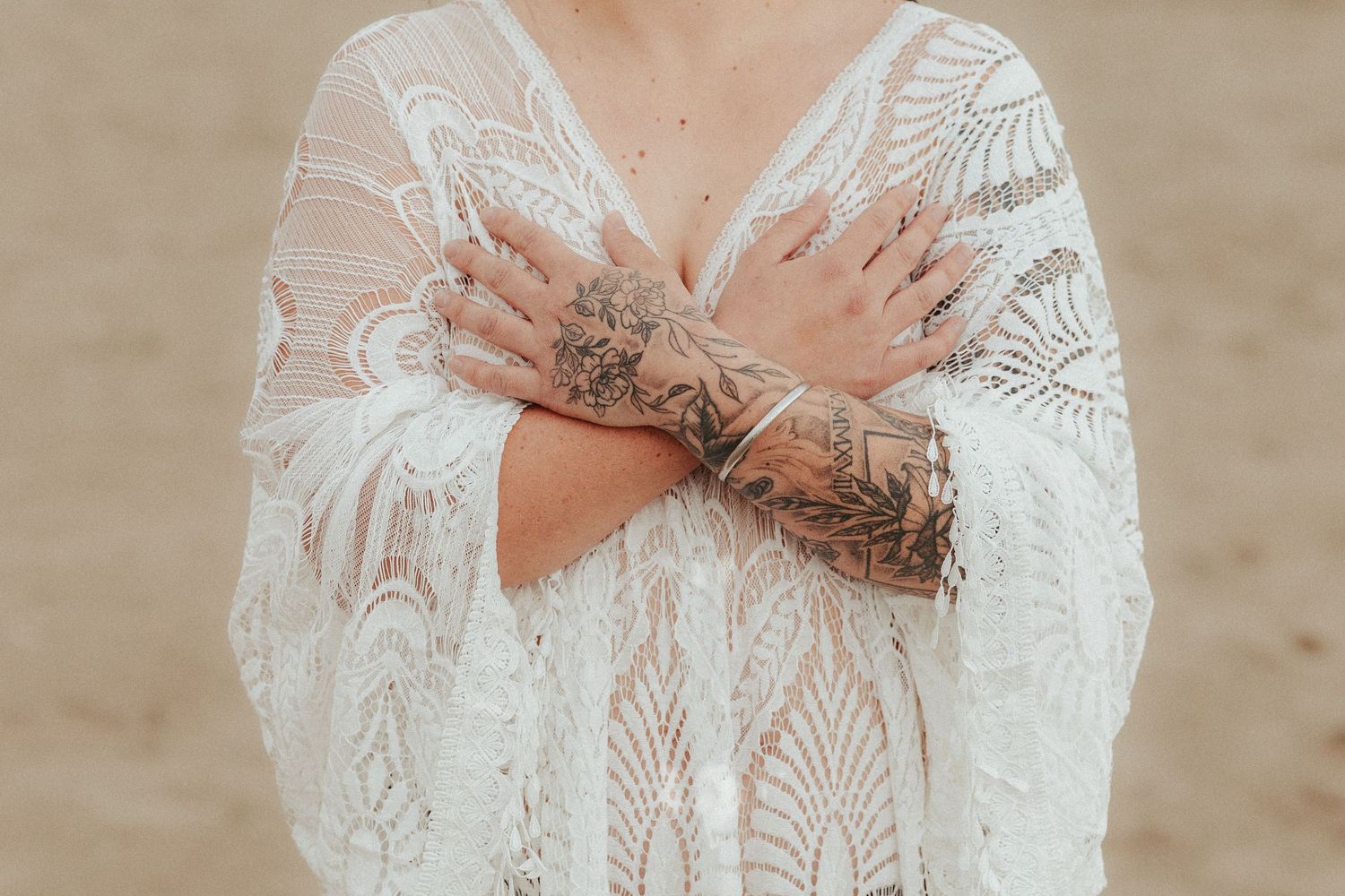 Detailed shot of intricate white lace dress with delicate hand placement.